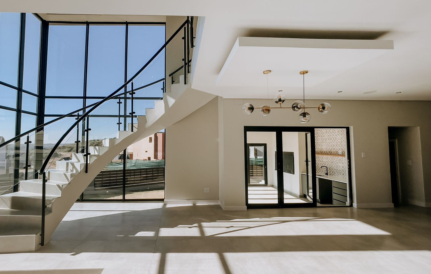 Modern minimalist interior spaces with large windows and clean white walls create an open, airy architectural design.
