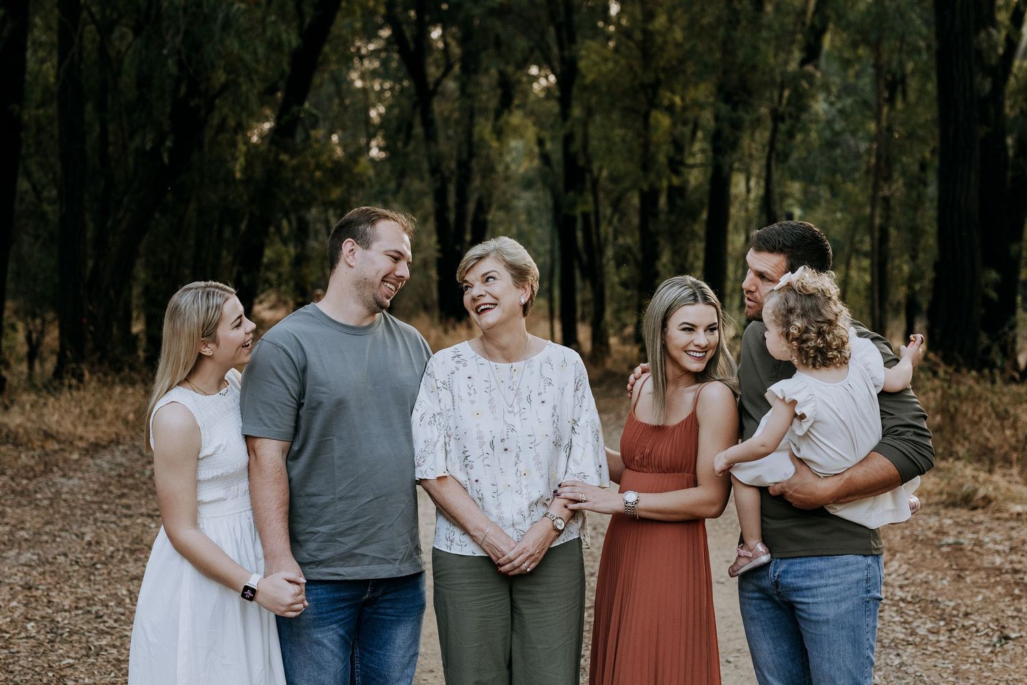 Small family group gathering and walking together in a wooded autumn forest setting.