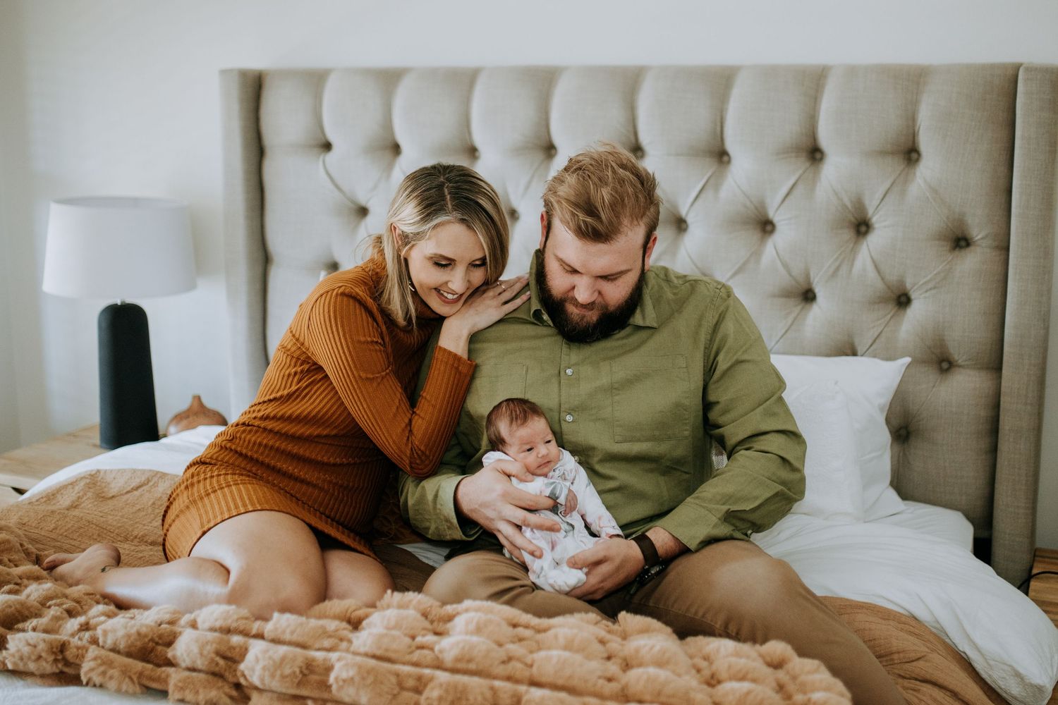 Family members share intimate moments together while relaxing on a tufted headboard bed.
