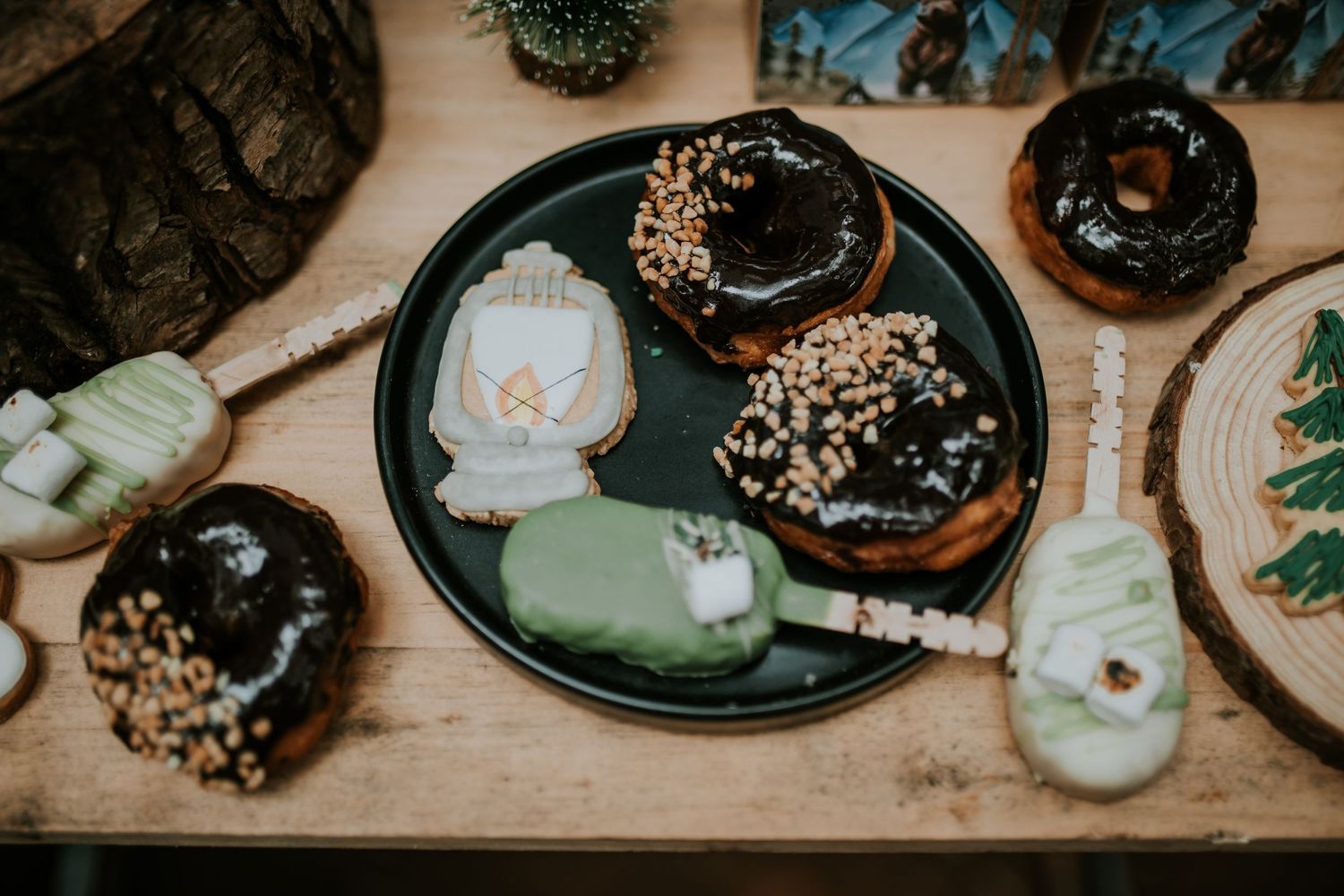 Overhead view of colorful donuts with chocolate, vanilla, and sprinkle toppings arranged in a row on wooden surface.