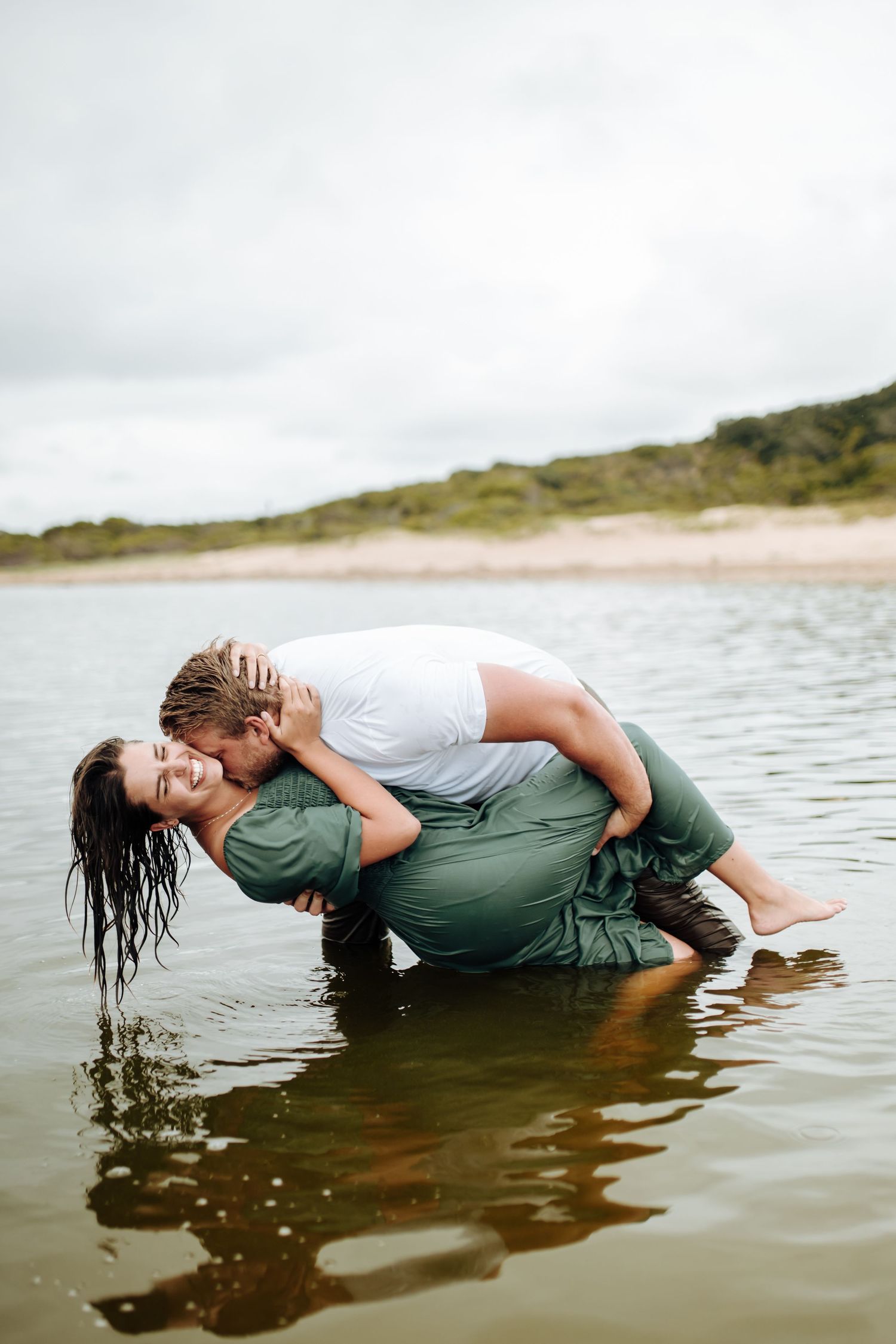 A sequence of someone floating in shallow water while posing artistically in green pants and white shirt.