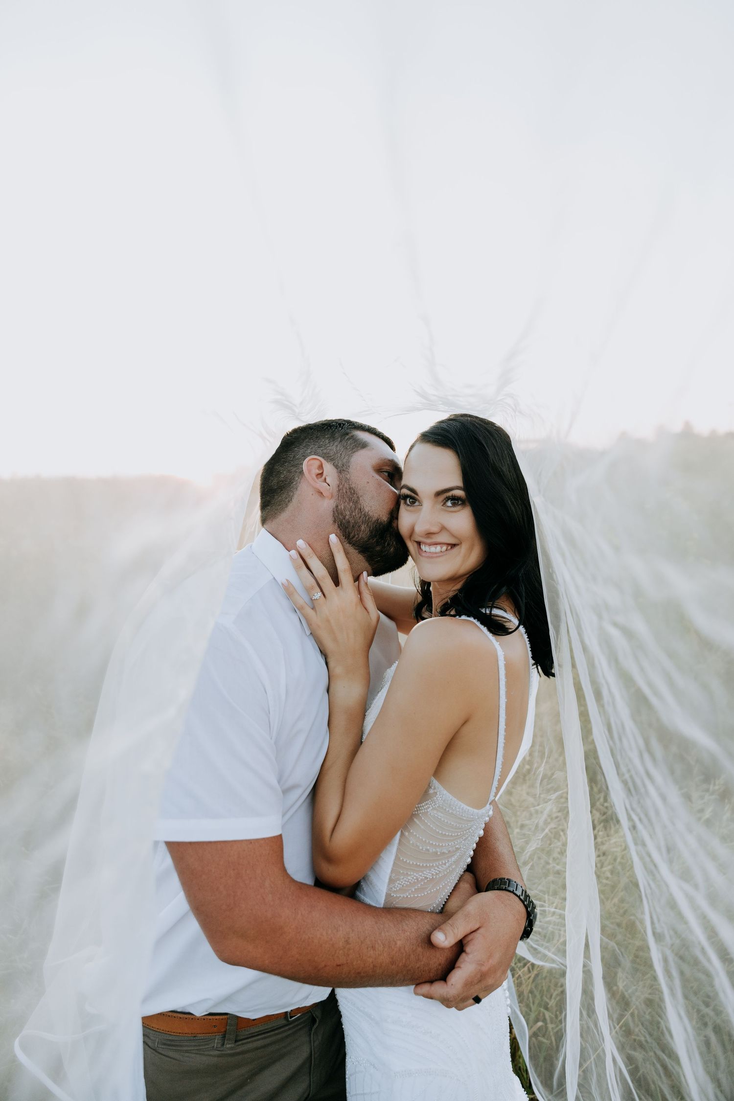 Intimate couple's portrait session against white fabric backdrop.