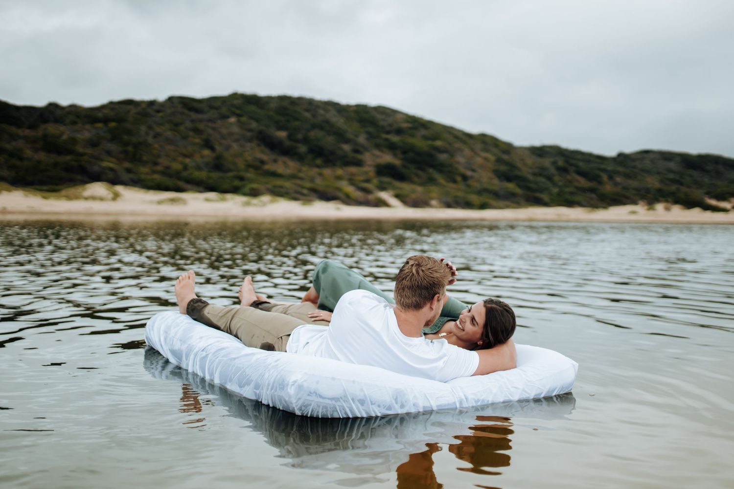 Person floats serenely in crystal-clear water while wearing white clothing and creating ripples on the surface.