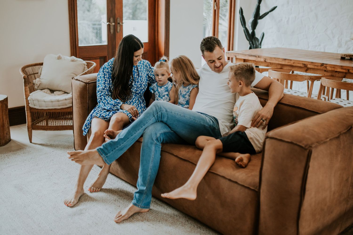 Family relaxing and spending quality time together on a comfortable brown leather couch in a bright living room.