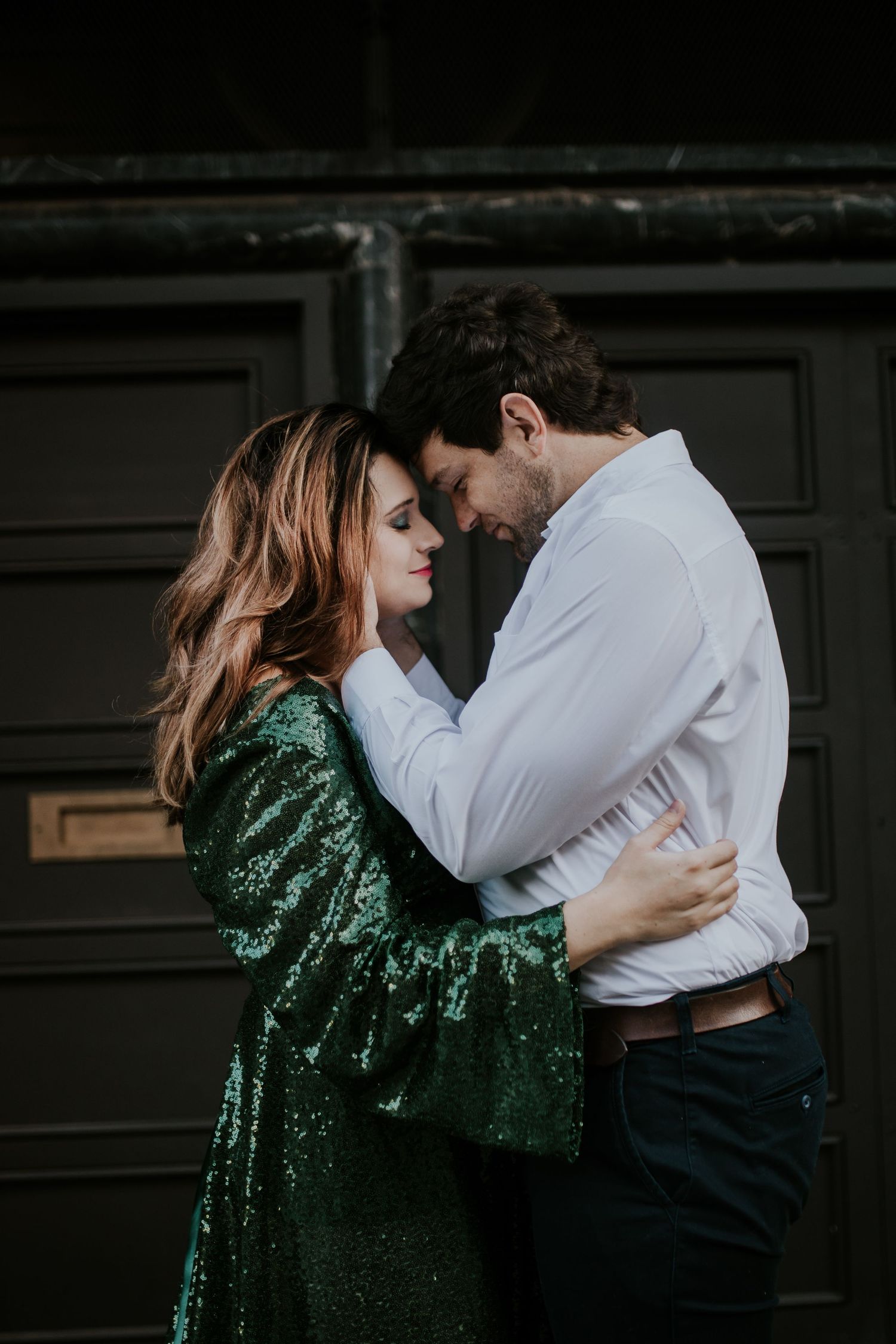 A couple dances intimately together with the person wearing a shimmering emerald green sequined dress.