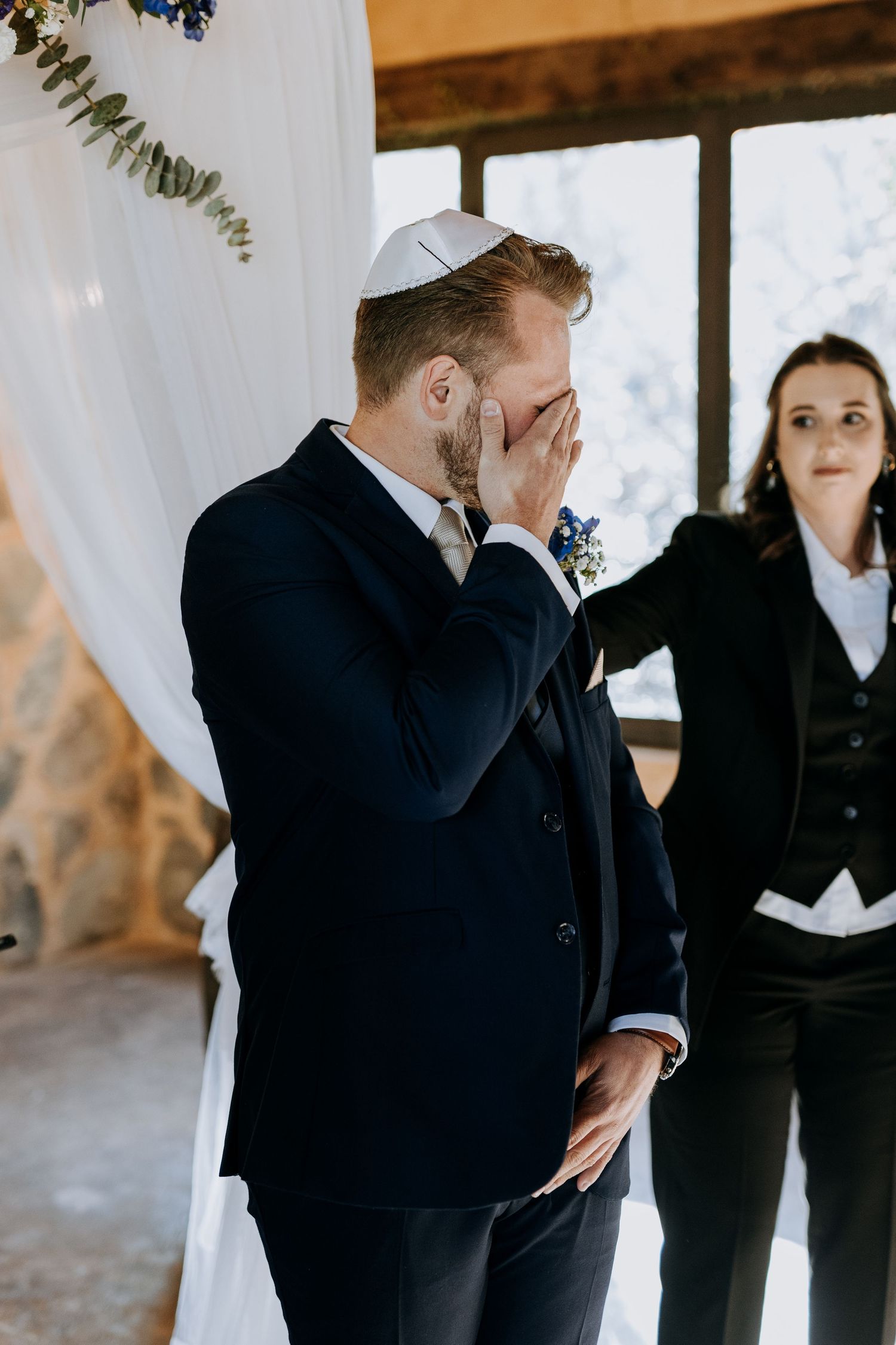 A sequence of emotional first look moments between people in formal wedding attire against a light backdrop.