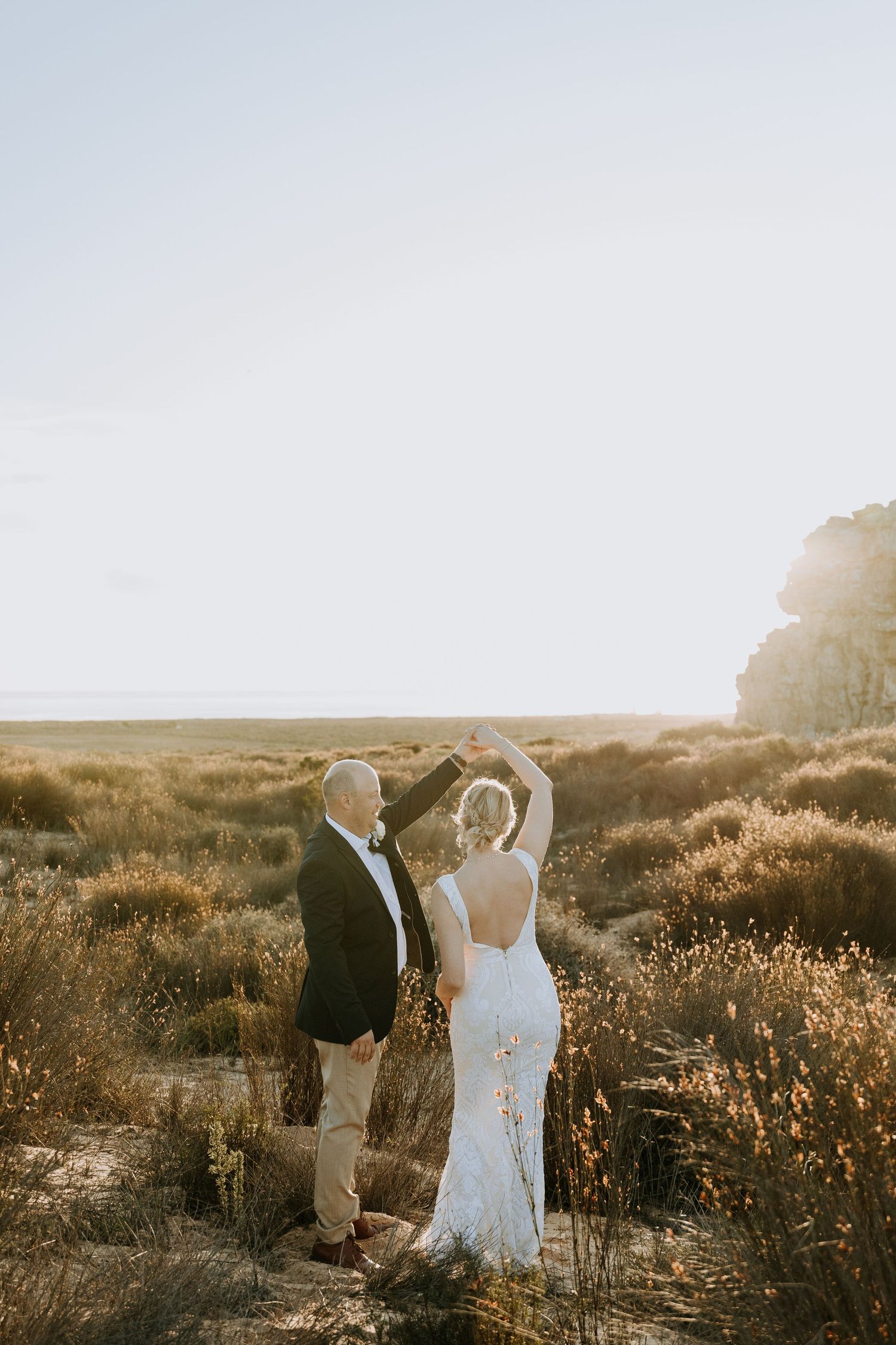 Two figures stand together in a golden field at sunset as sunlight bathes the landscape in warm autumn hues.
