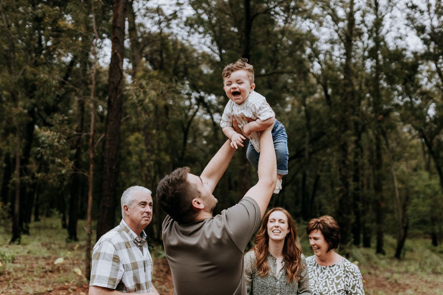 Happy family enjoying playtime together outside in a wooded area during an autumn day.