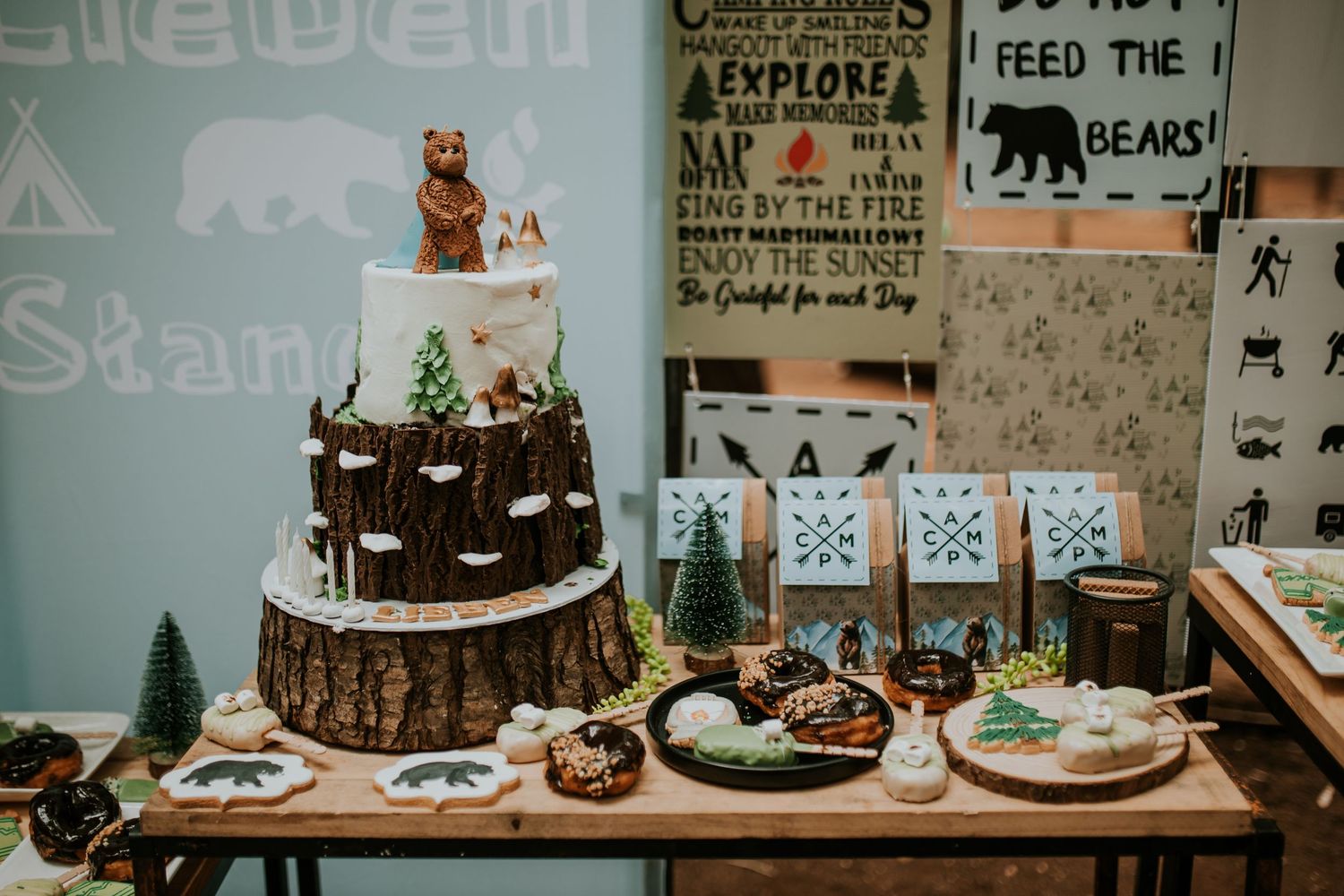 A woodland-themed dessert table features rustic decor, cake, and party treats arranged on a wooden surface.