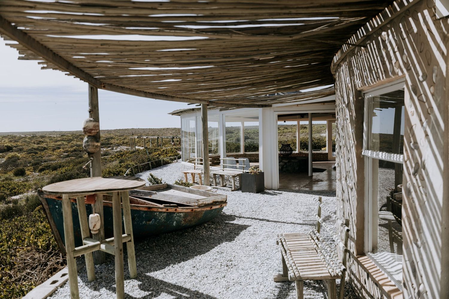 Rustic outdoor wooden pergola with hanging string lights creates a cozy dining atmosphere in a backyard garden setting.