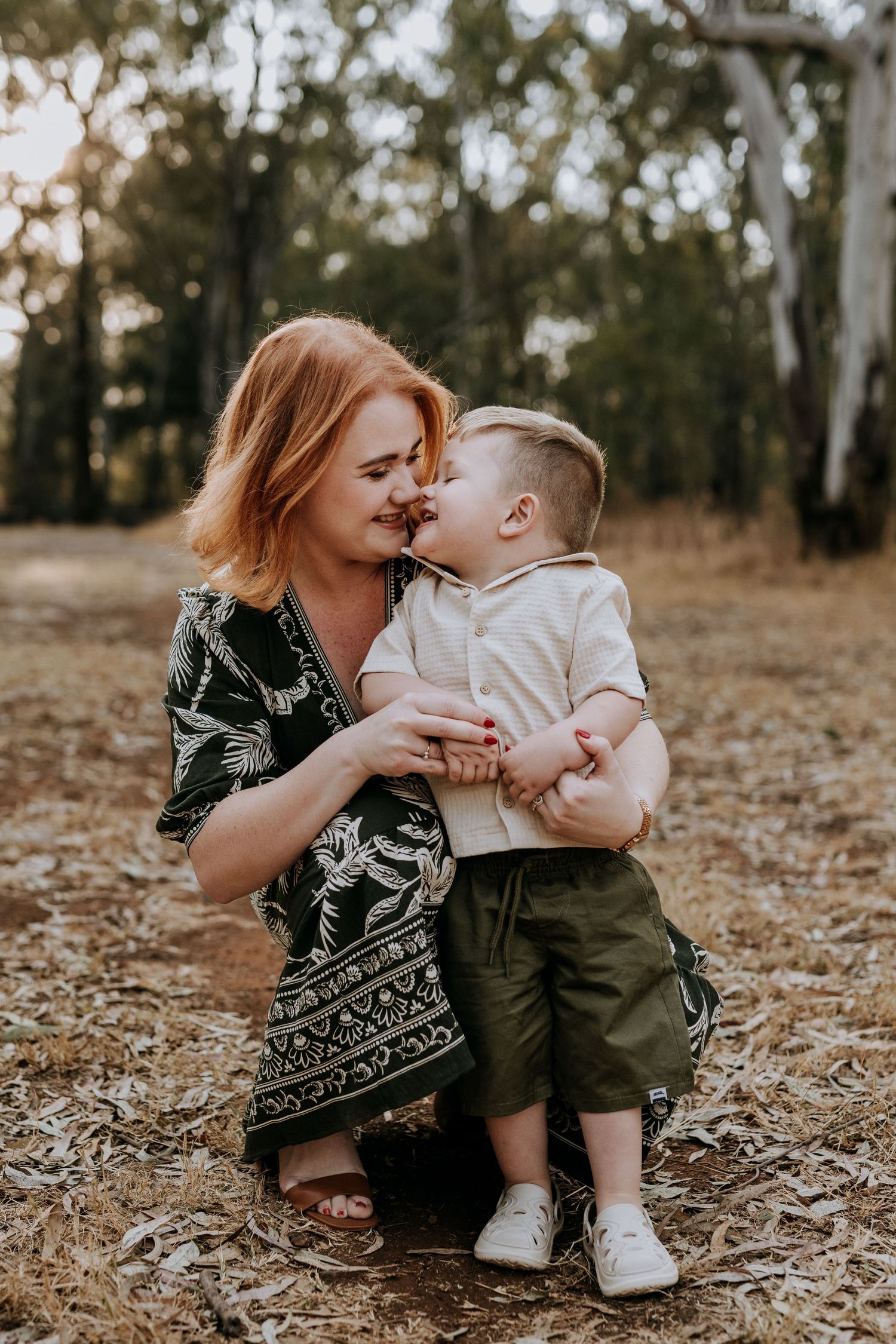 Sweet moment shared between parent and child playing together on fallen autumn leaves in a wooded outdoor setting.