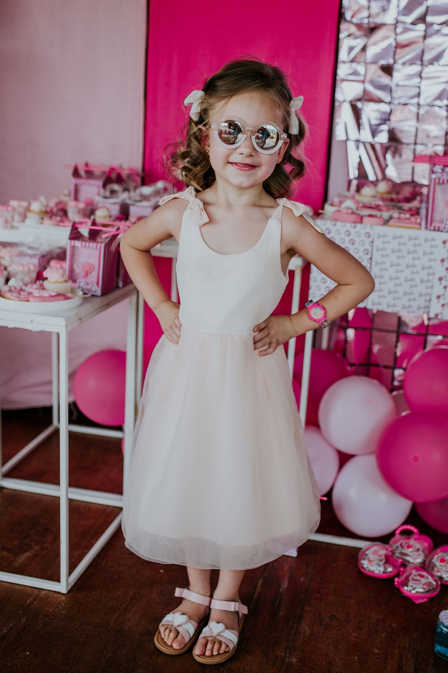 A child in a white party dress and glasses poses with balloons in a pink-decorated room at different angles.