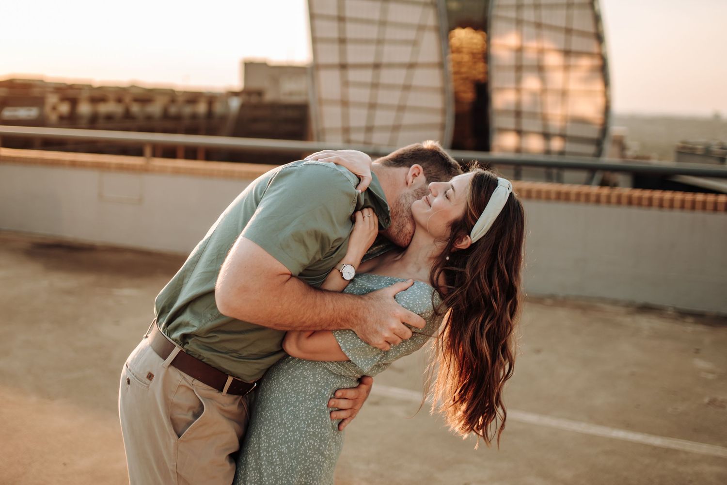 Romantic couple dances together on an urban rooftop at sunset while embracing passionately.