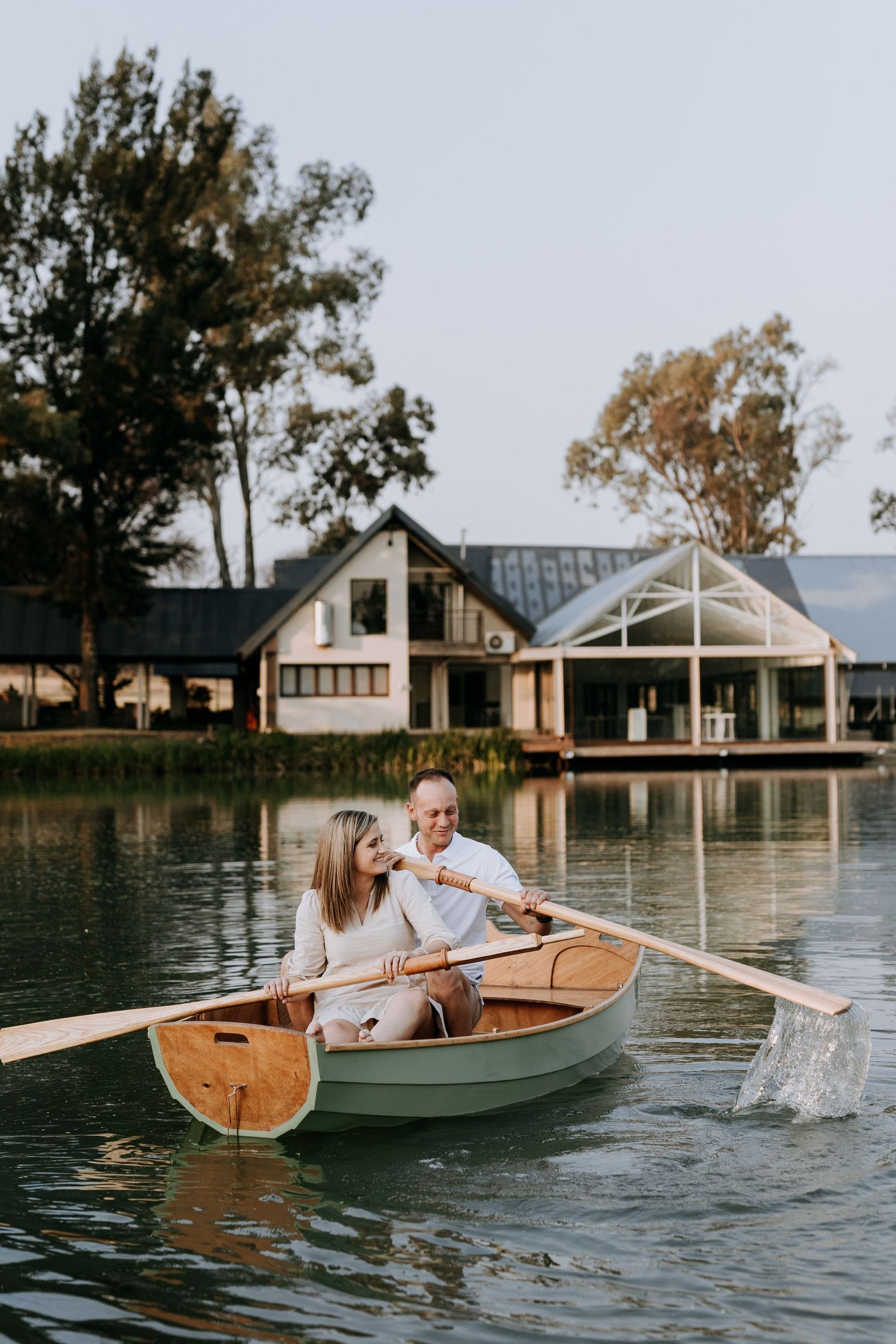 Four connected images show a couple enjoying a romantic boat ride on a lake with waterfront homes in the background.