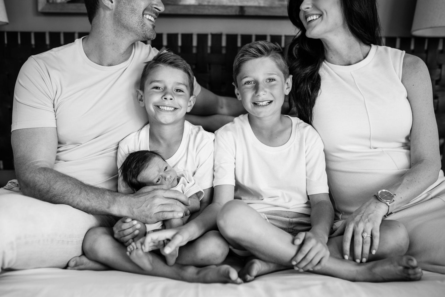 A series of candid black and white family photos showing parents and children sitting together wearing white shirts.