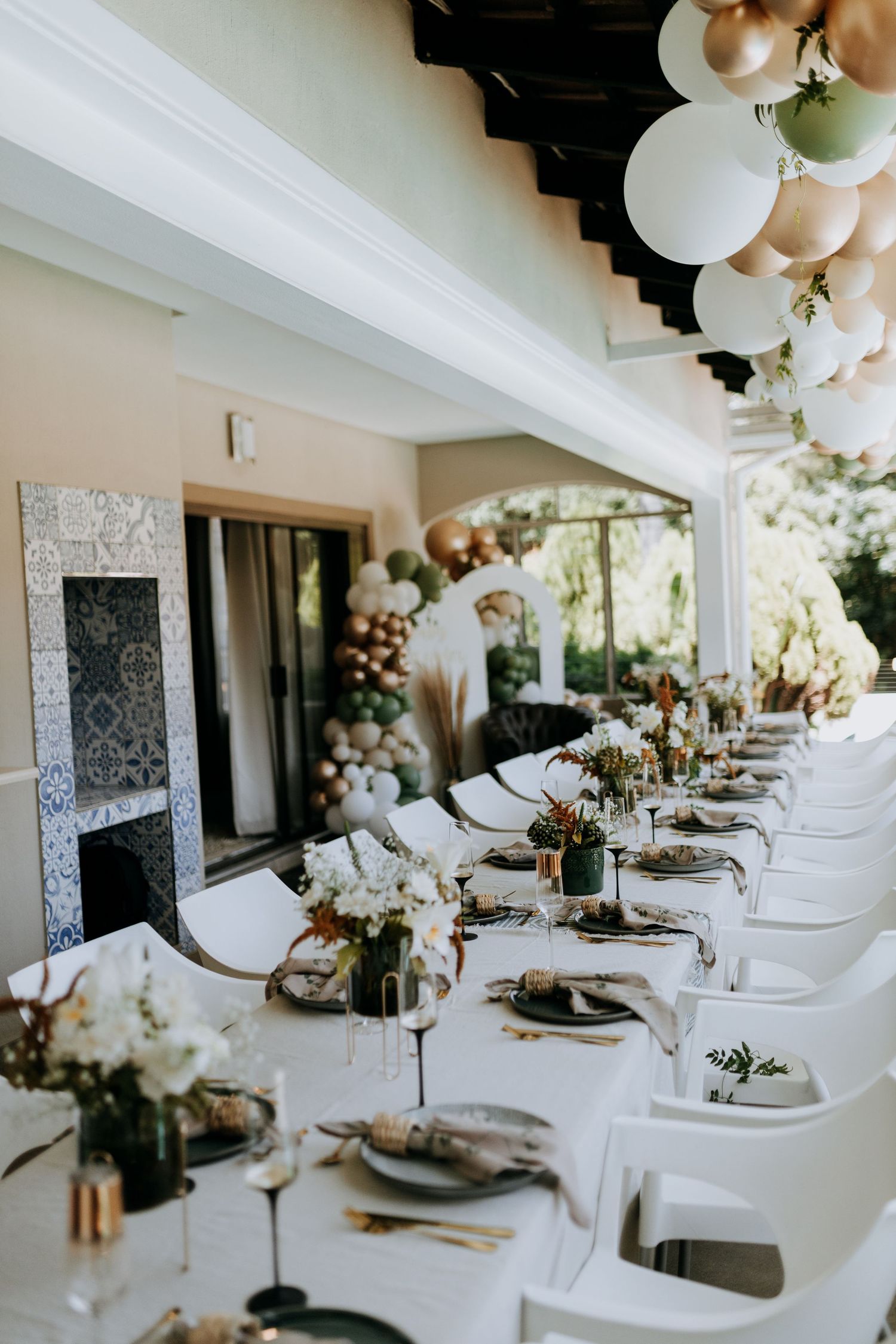 Elegant wedding reception table settings with white linens, balloon decor and natural greenery in a bright modern venue.