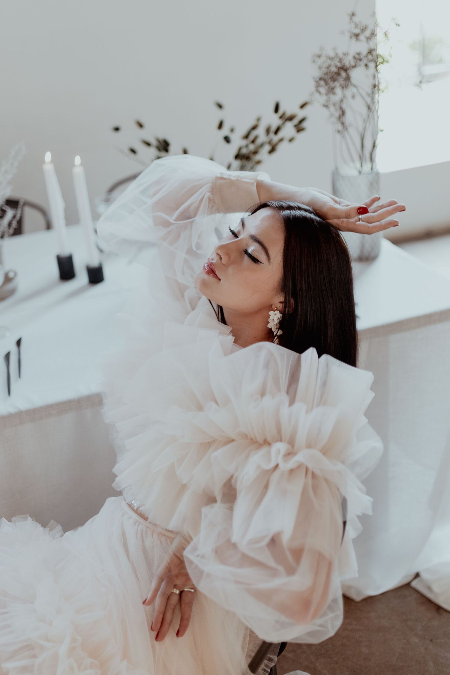 Ethereal fashion photo series showing dramatic poses in flowing white tulle gown against minimal backdrop.