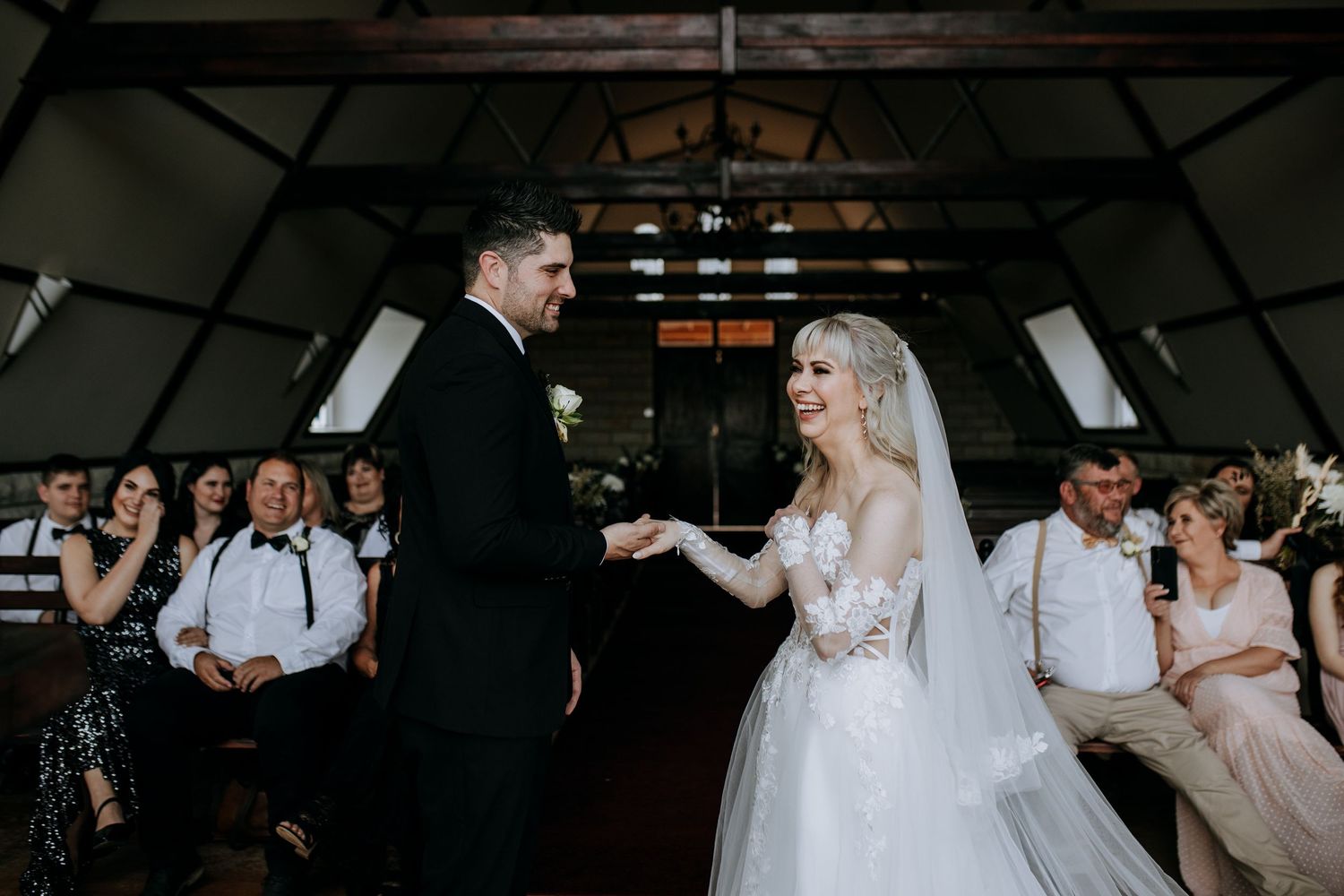 A couple shares a romantic dance at their wedding reception in a dimly lit rustic venue.