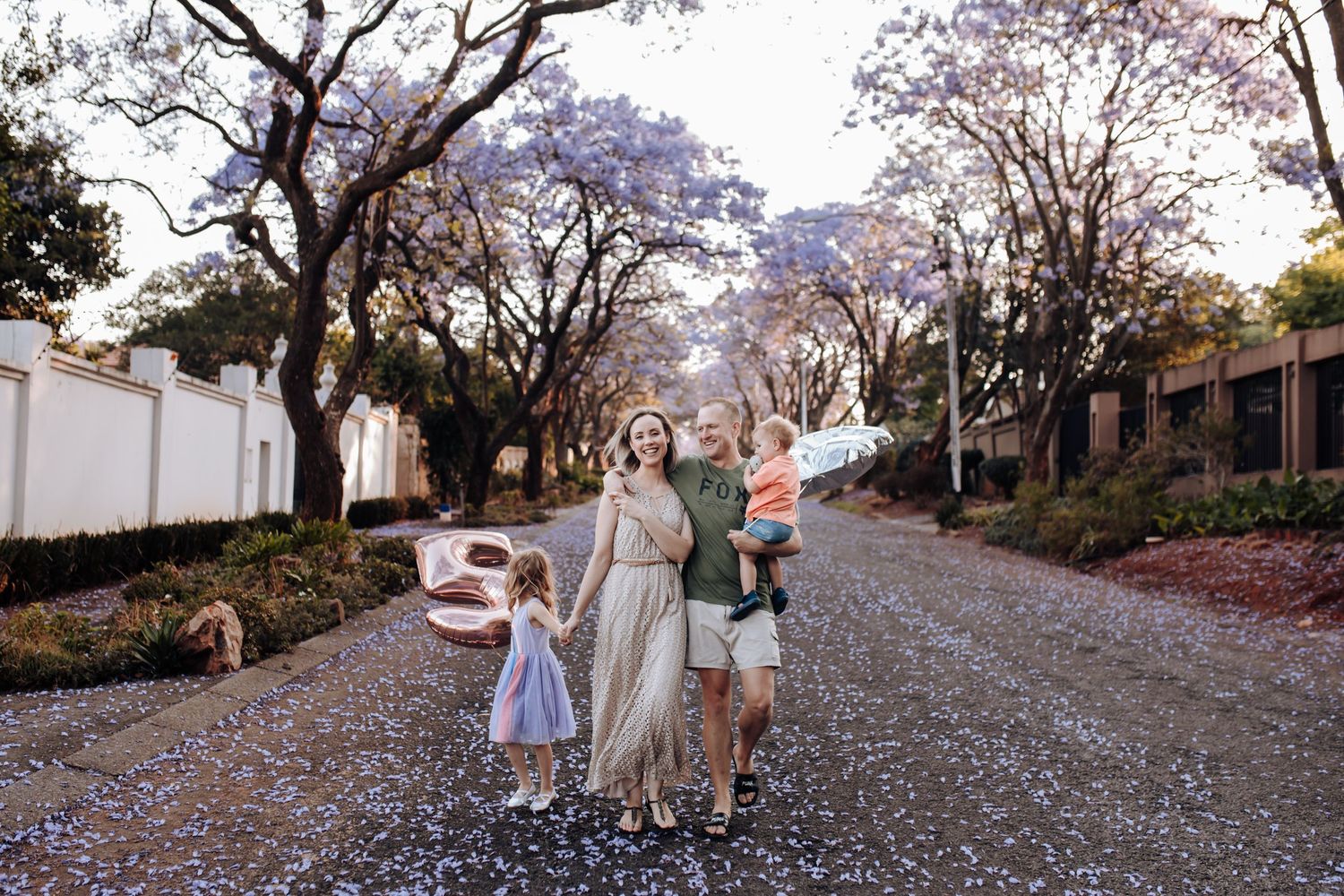 People walking down a scenic path covered in vibrant pink cherry blossom petals during spring bloom.