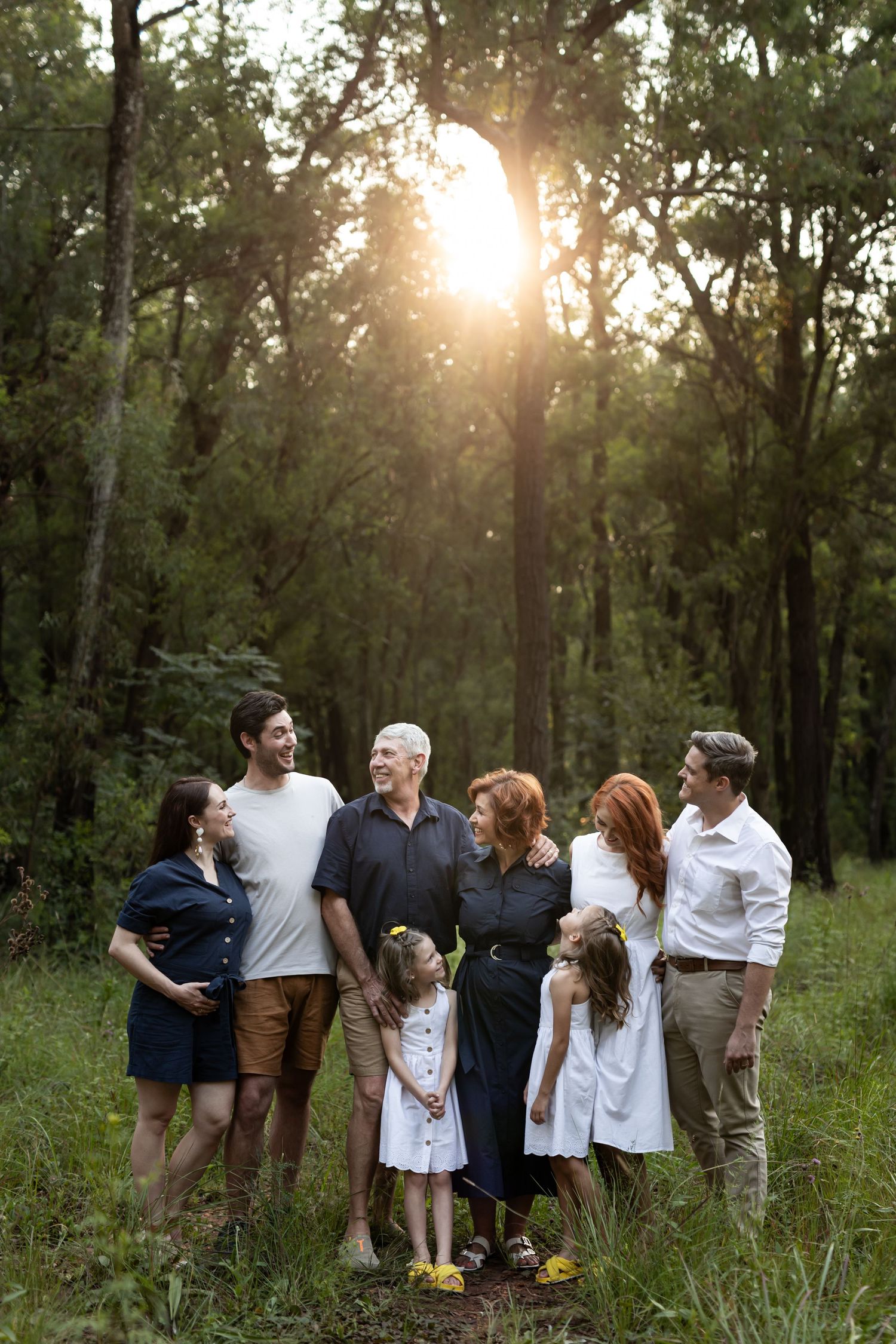 A group walks through a sunlit forest setting during magic hour with sun rays streaming through the trees.
