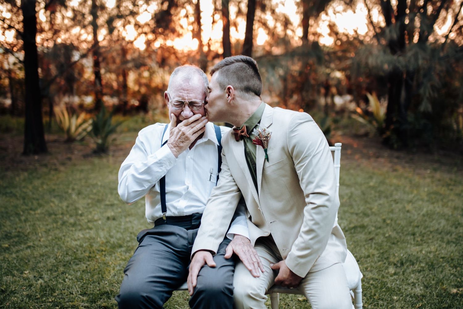 Loving golden hour outdoor portrait of elderly couple in white outfits sharing tender moments together in a park setting.