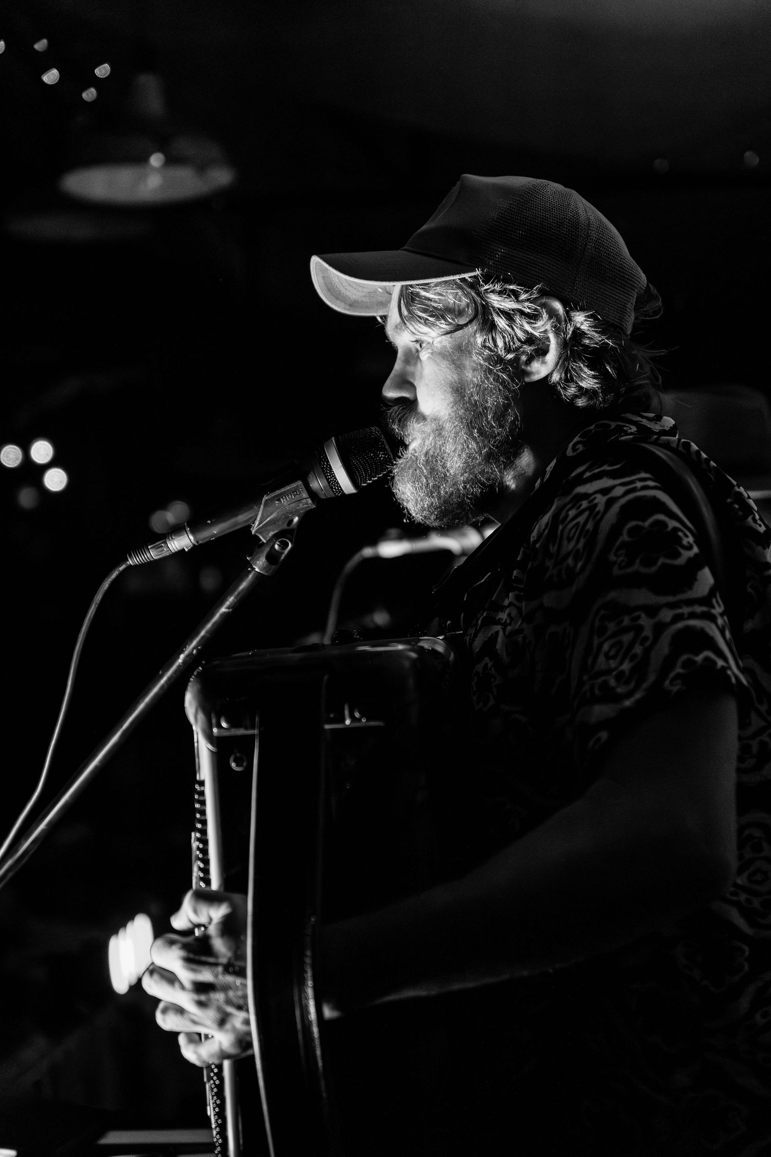 Black and white photos show a musician performing on stage with a guitar under dramatic concert lighting.