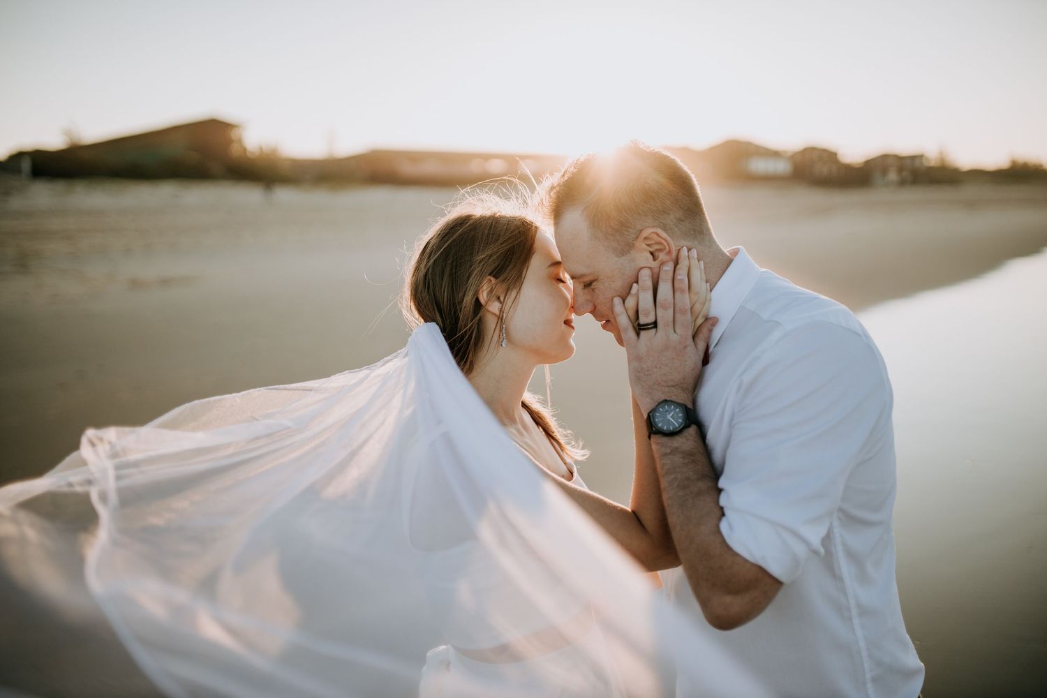 Romantic couple shares tender moments in golden sunlit field wearing coordinated blue and white outfits for engagement photos.