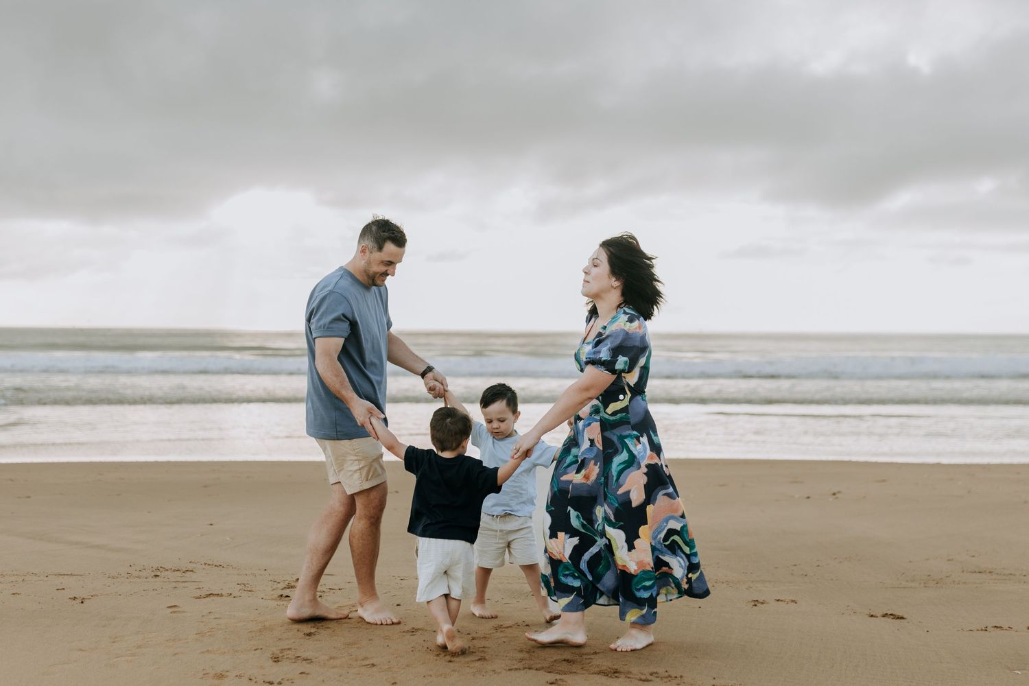 Family enjoying quality time together while walking along a scenic beach during sunset.