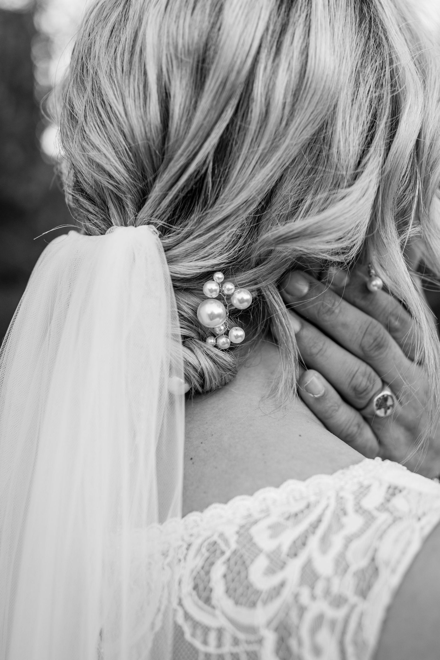 Close-up view of a delicate lace veil attachment with pearl details in black and white.