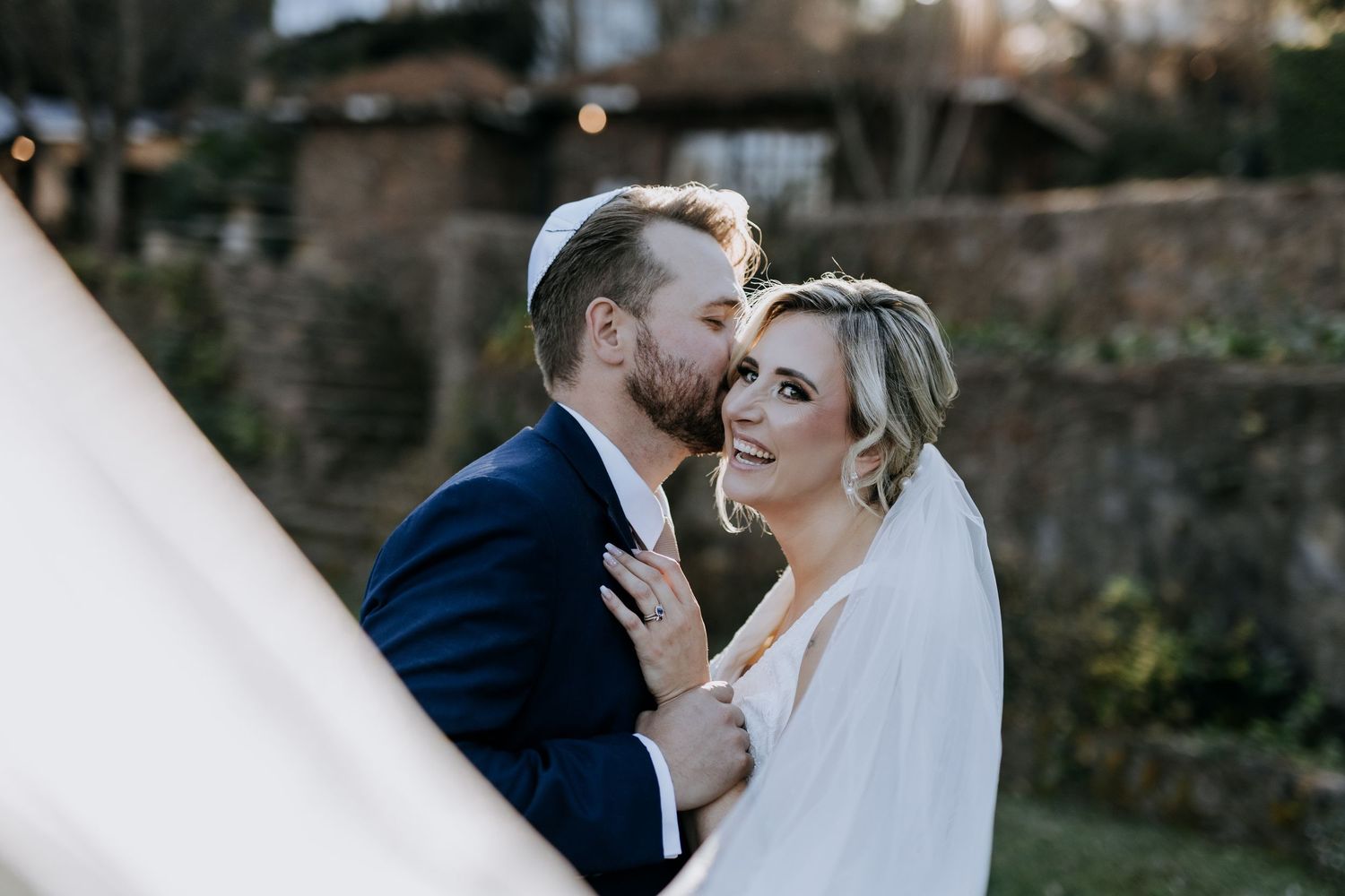 A bride and groom share an intimate moment outdoors during their wedding photoshoot.