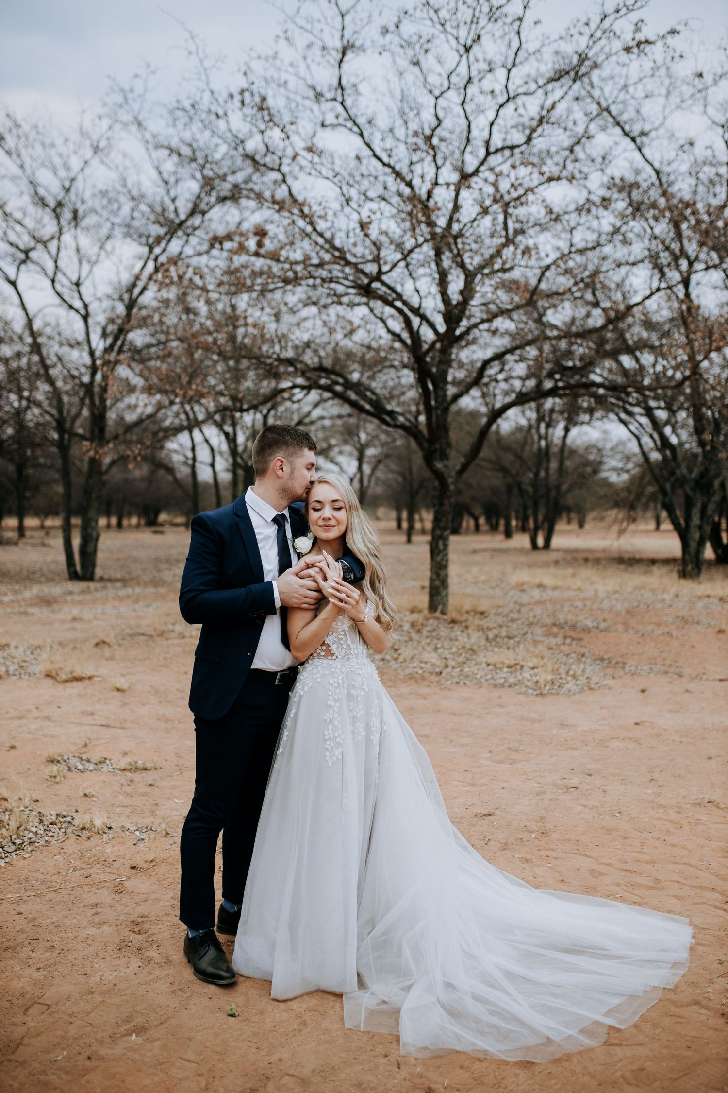 Wedding couple shares romantic moment in desert landscape.
