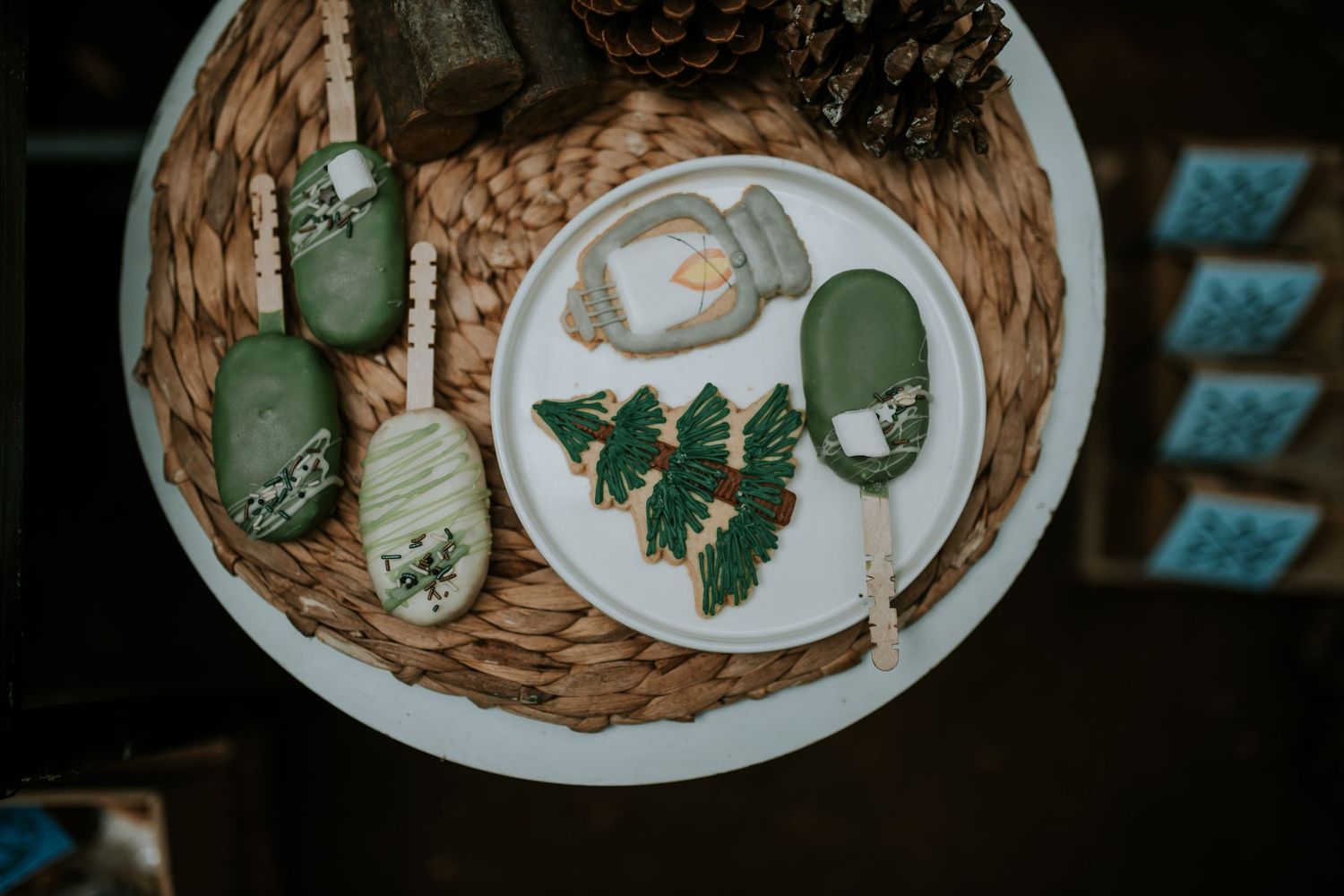 Assortment of elegantly plated Christmas cookies with green and white icing arranged on rustic woven placemats.
