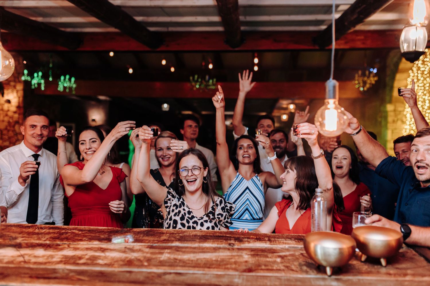A lively dance party scene in a dimly lit venue with a crowd of energetic people celebrating and dancing together.