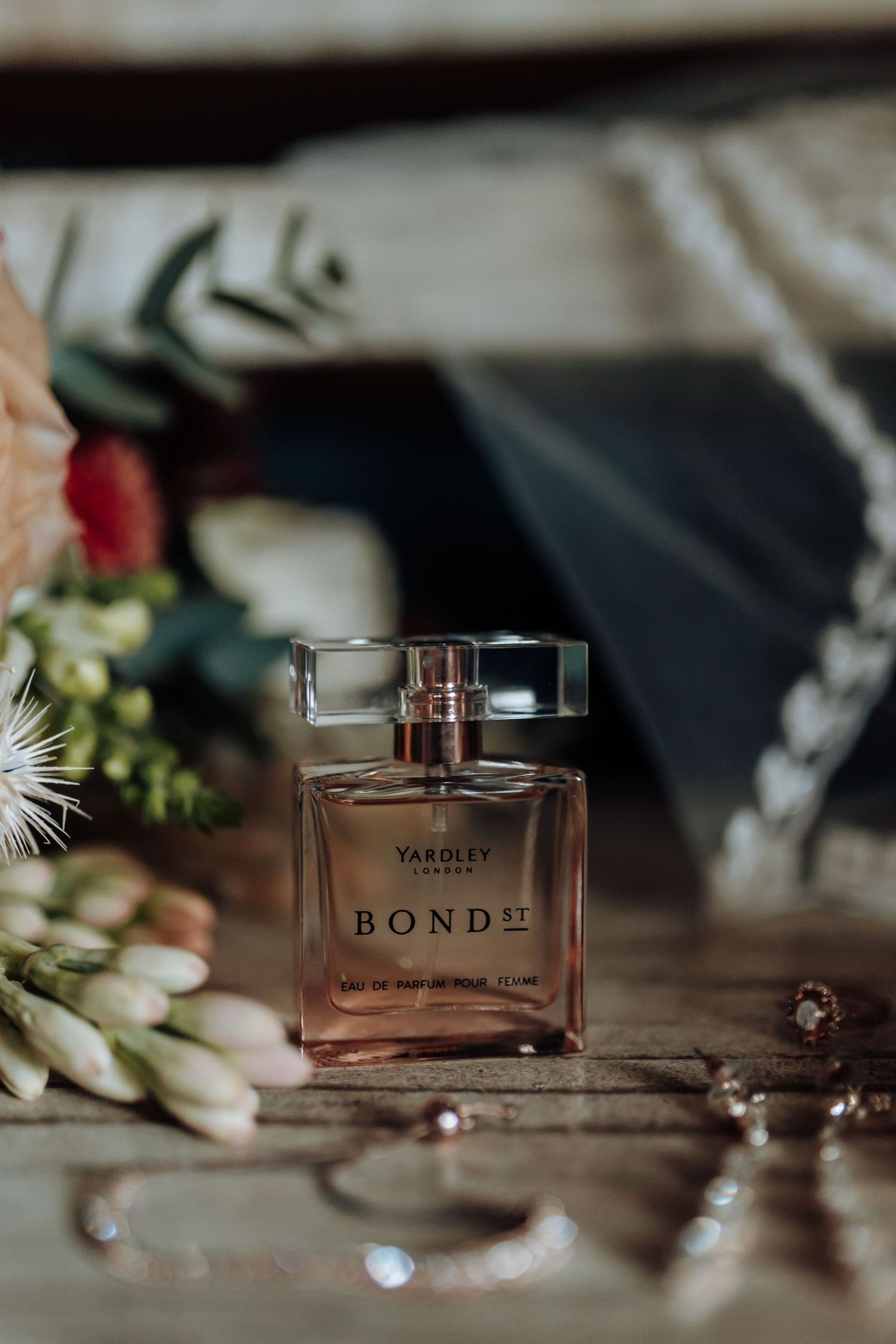 Close-up sequence of perfume bottles and floral styling elements in warm lighting against dark background.