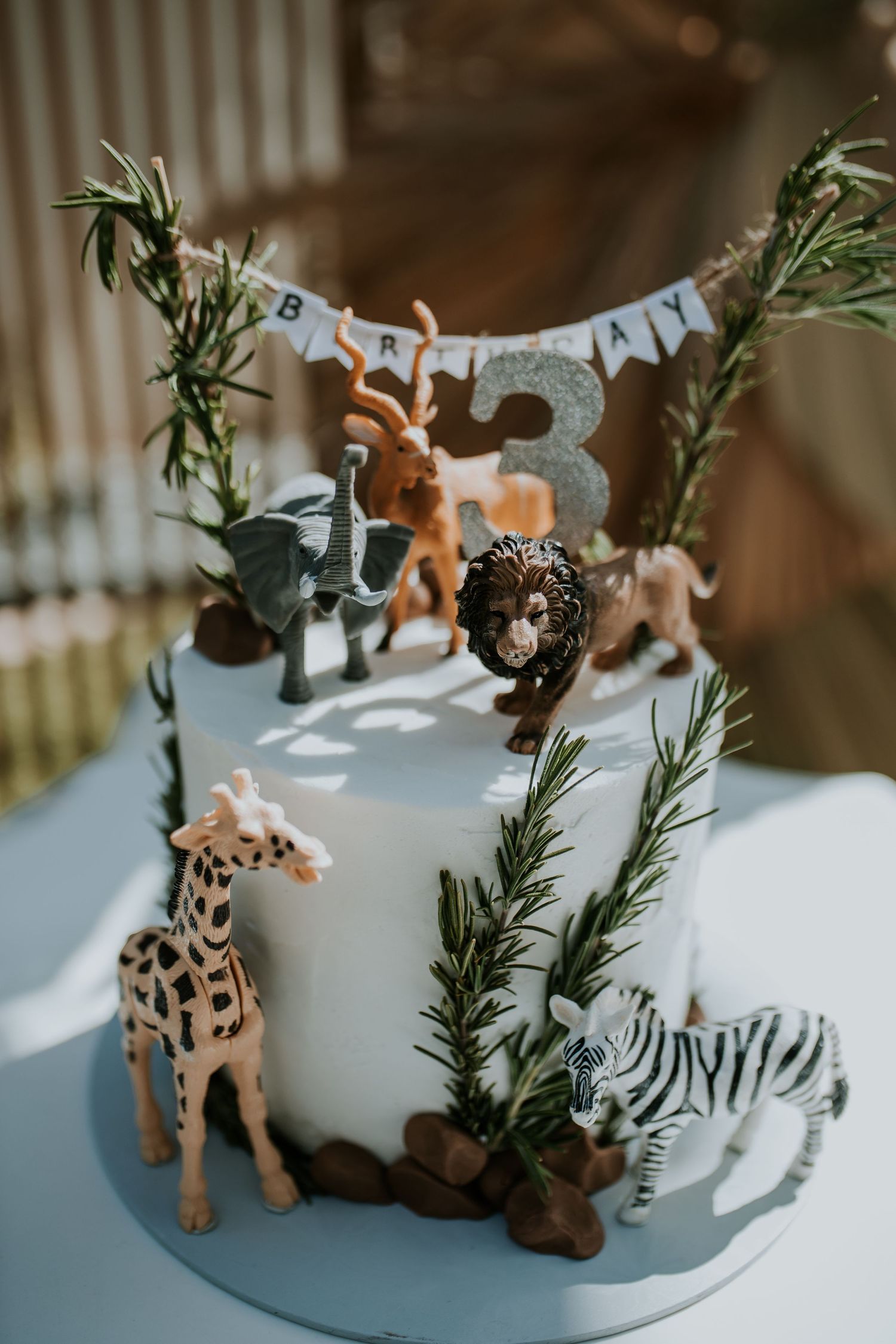 Miniature deer toys arranged with pine branches and snow-like decor on a cake in a misty winter forest scene.