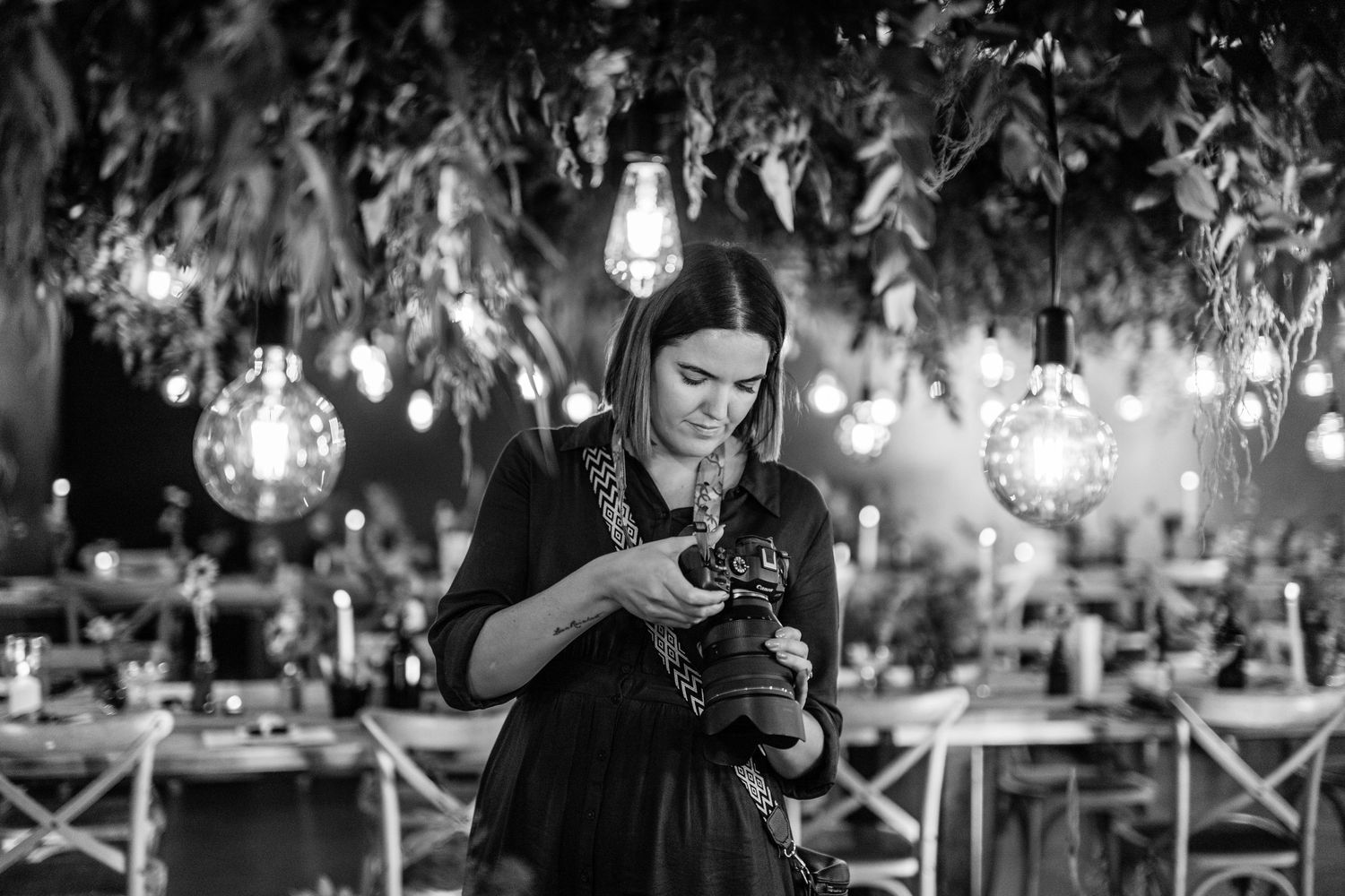 A wedding reception at night with hanging string lights creating a romantic outdoor ambiance.