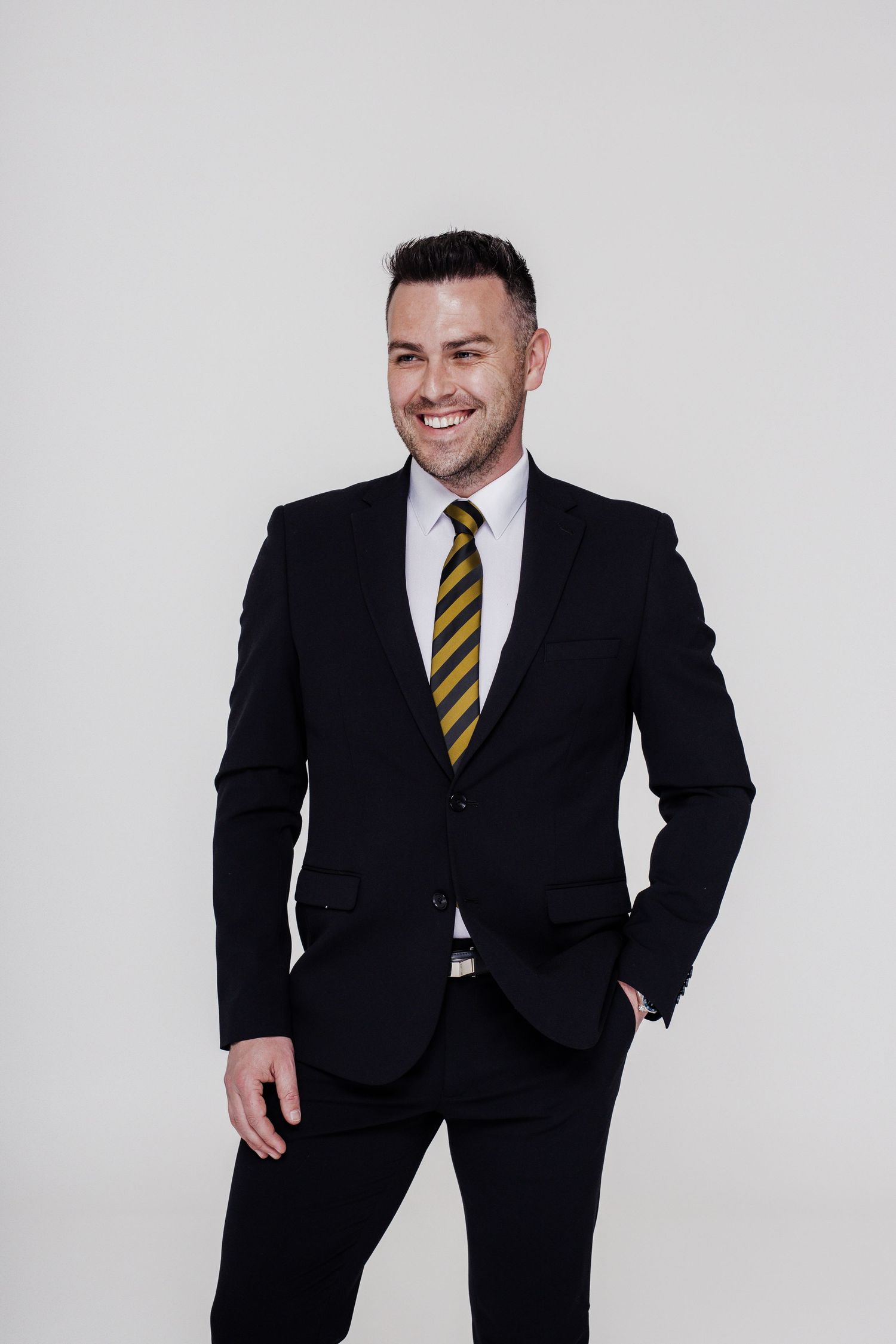 Professional wearing a dark suit with gold striped tie poses against white background in series of confident stances.
