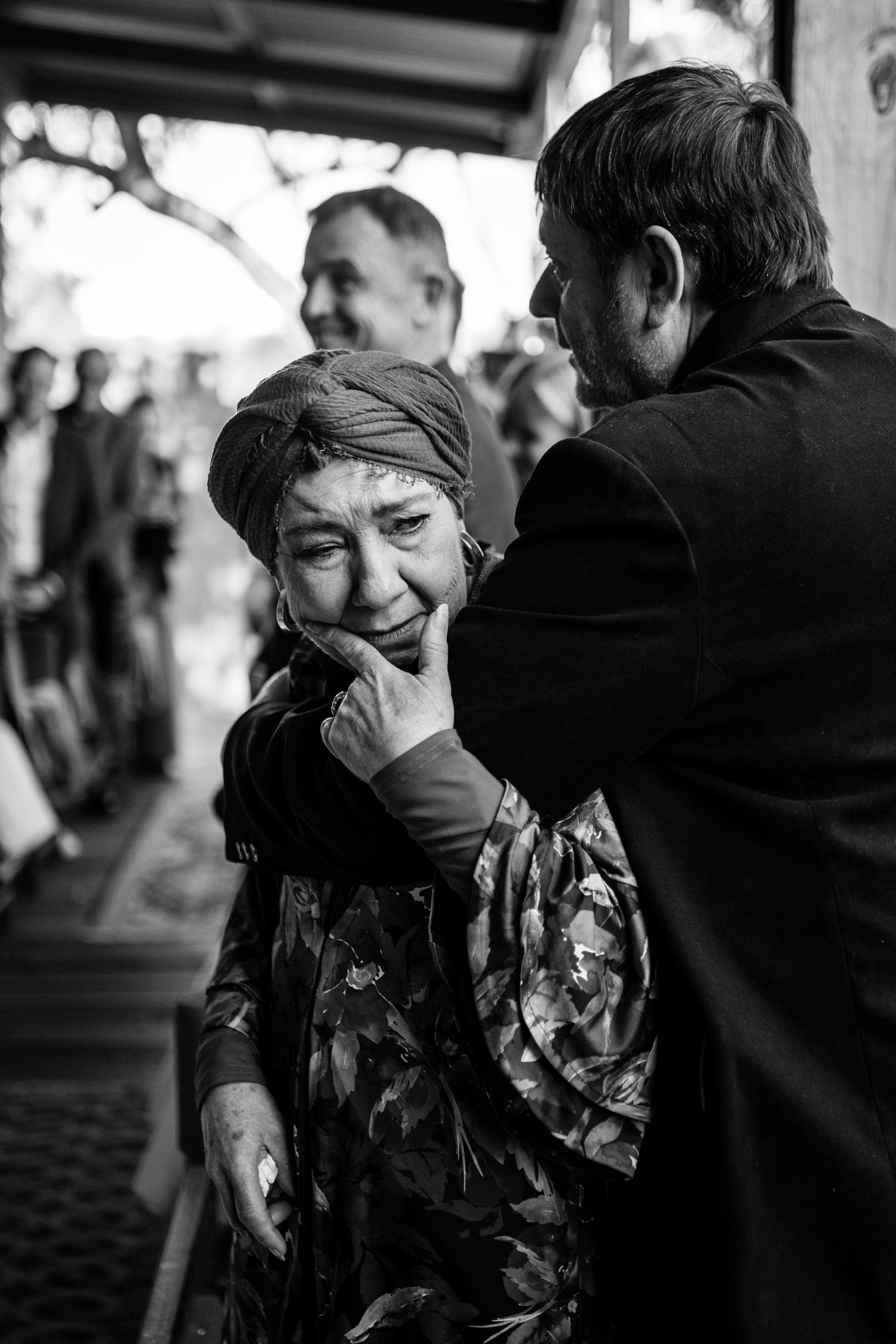 Emotional black and white candid moment between two people at social gathering.