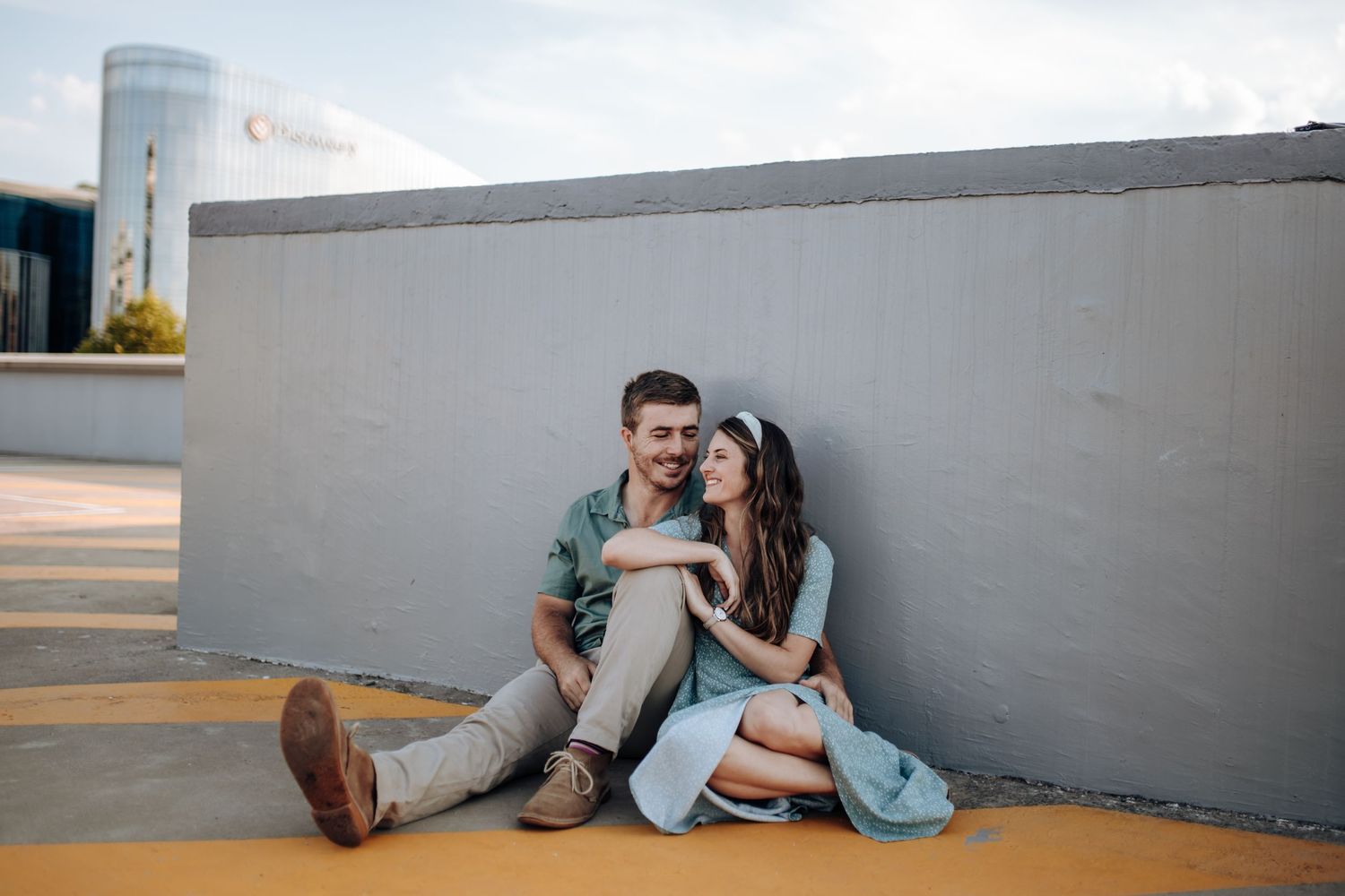 A couple sitting and embracing on the floor in front of a gray wall in varying casual poses.