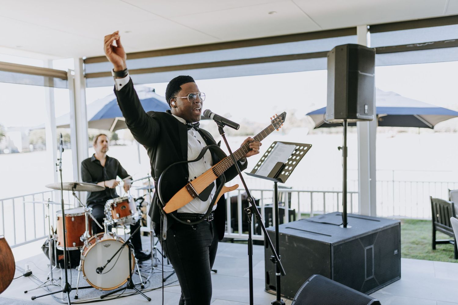 Musicians perform together in a bright modern studio space with large windows and white walls.
