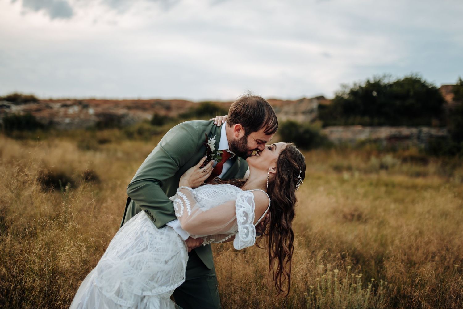 Romantic couple enjoying an intimate moment in a rustic outdoor meadow at sunset.
