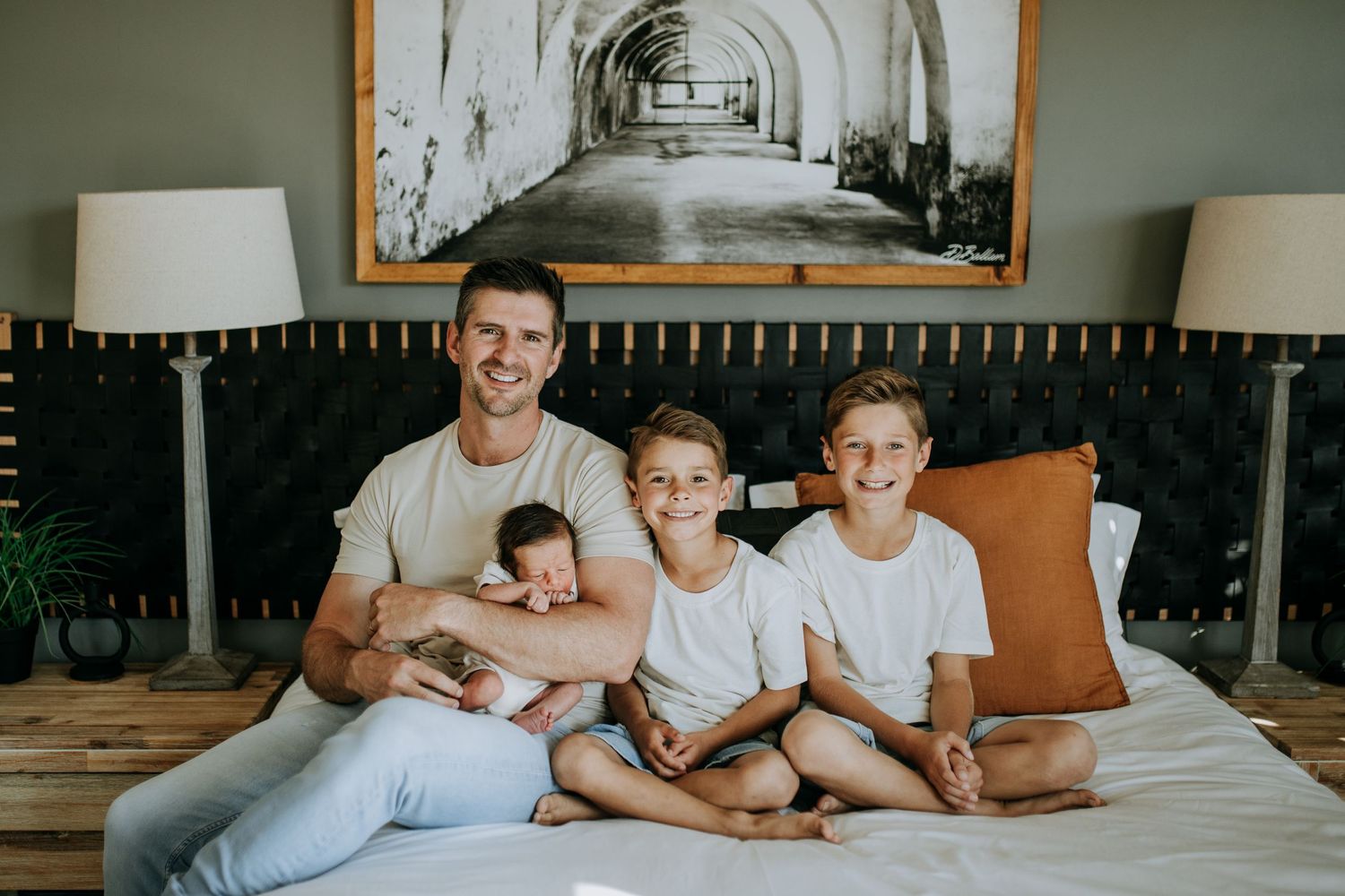 Family lounging together in a comfortable white bedroom while enjoying a relaxed weekend morning at home.