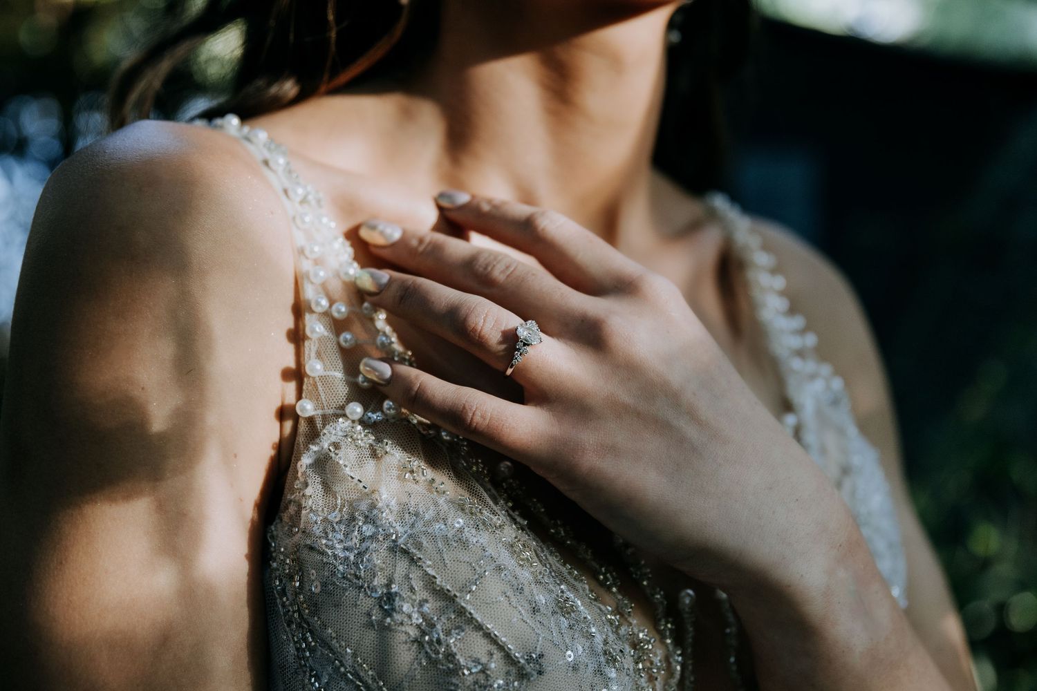 A person's shoulder and collarbone covered in shimmering glitter sparkles against a dark background.