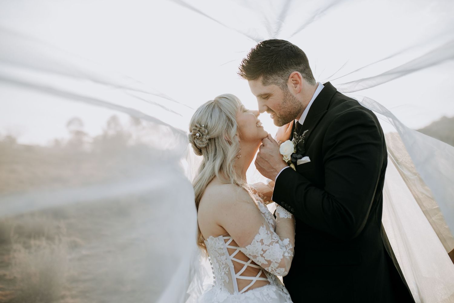 Romantic couple embraces in an intimate moment against a misty outdoor background.