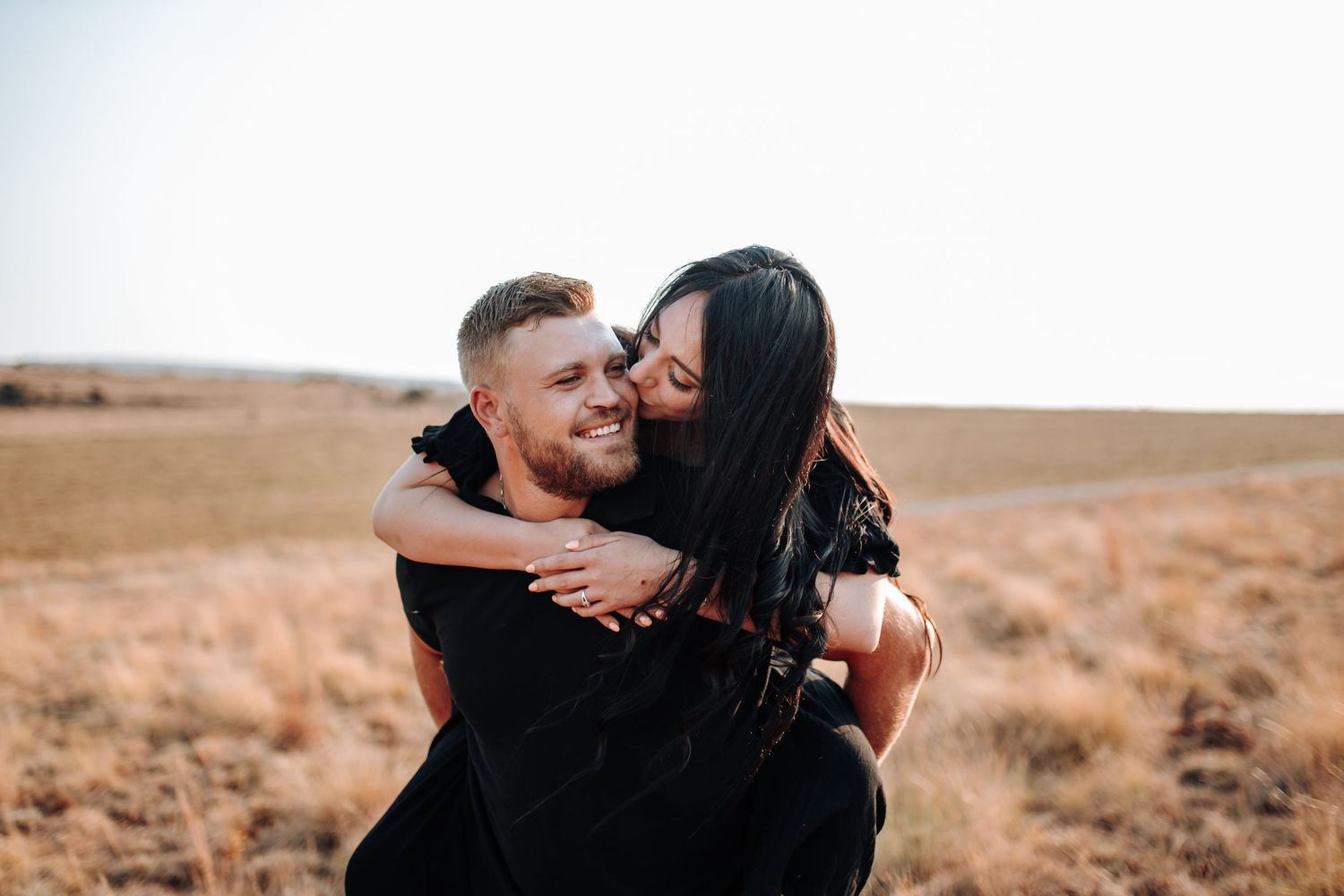Close-up photo of a joyful embrace in a golden field during sunset.