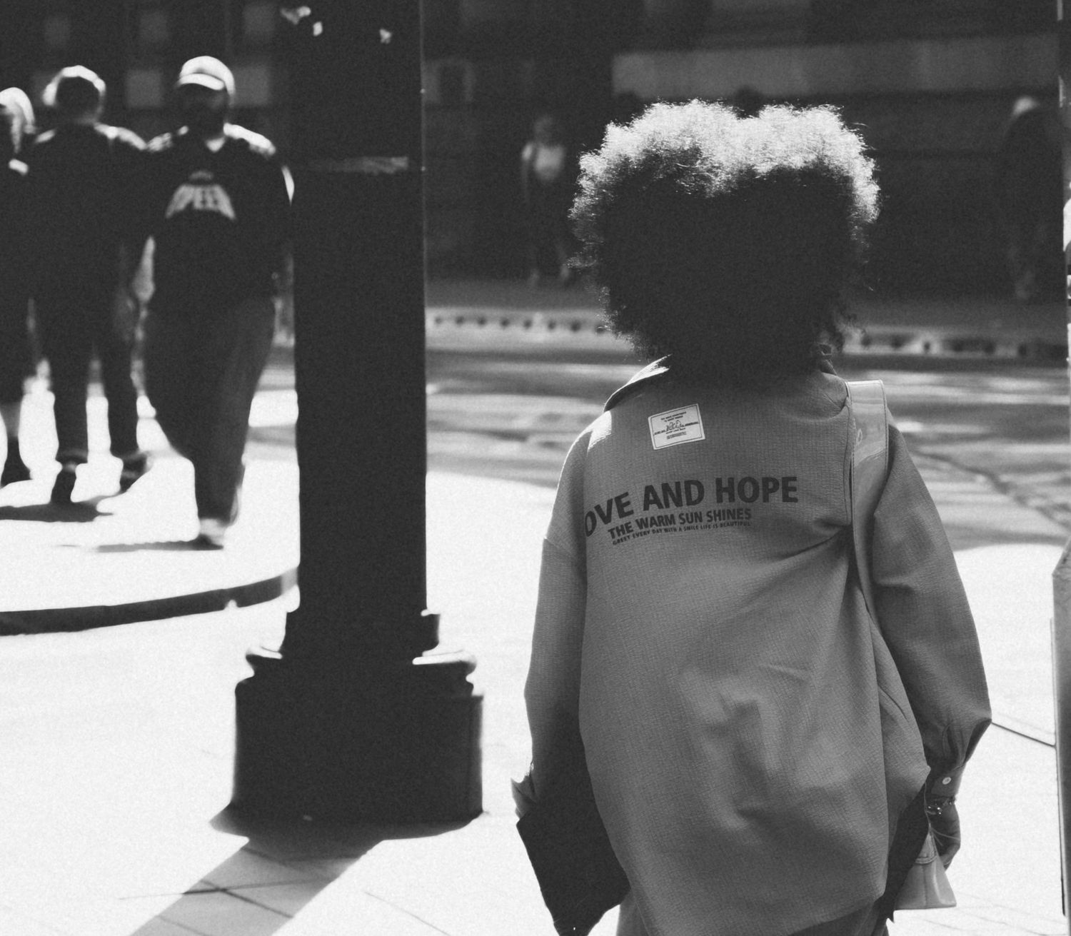 Manchester streets. A young gir with her back to the camera and light shining through her hair.