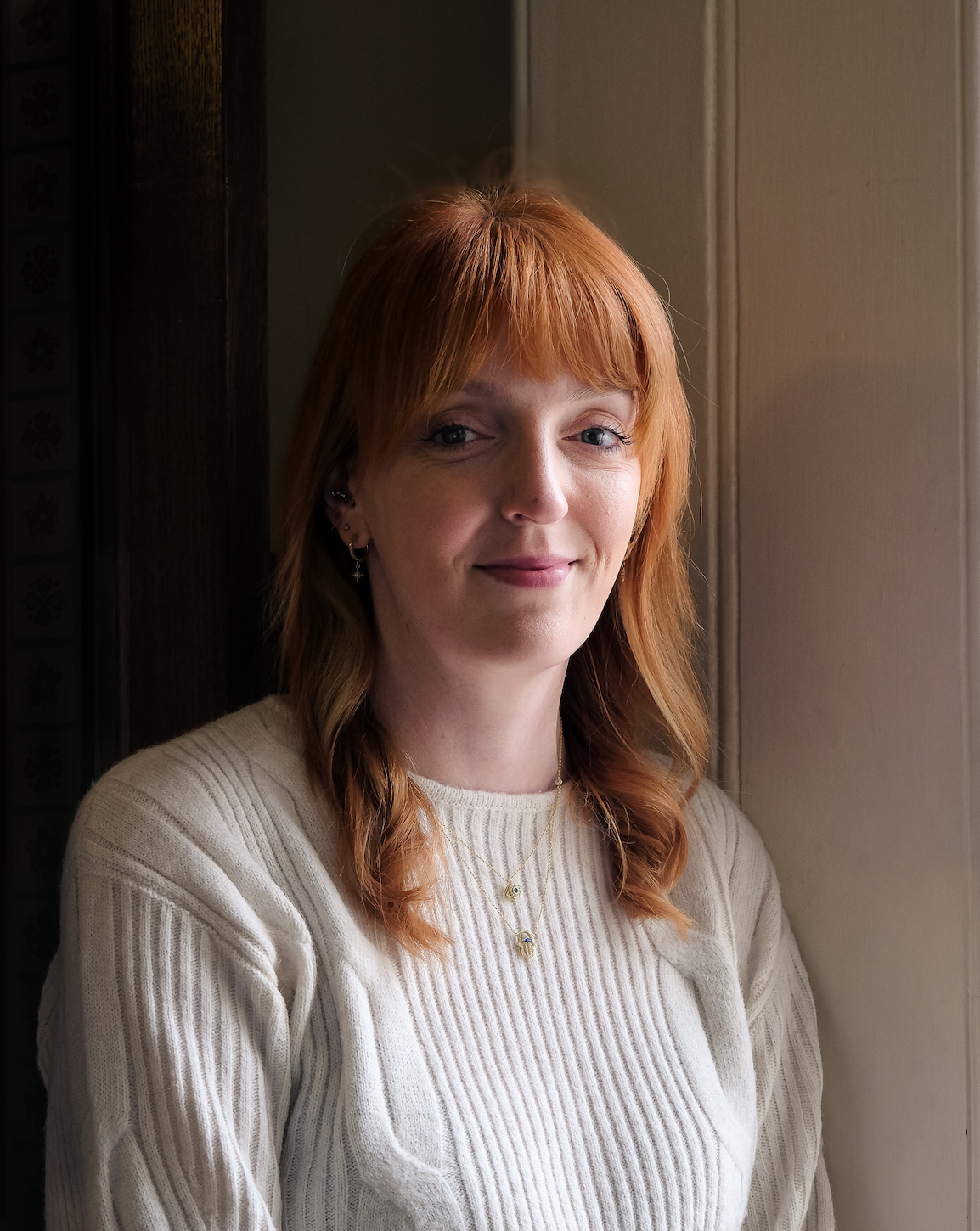 Charlotte Nichols, Member of Parliament stands by a window in natural light.
