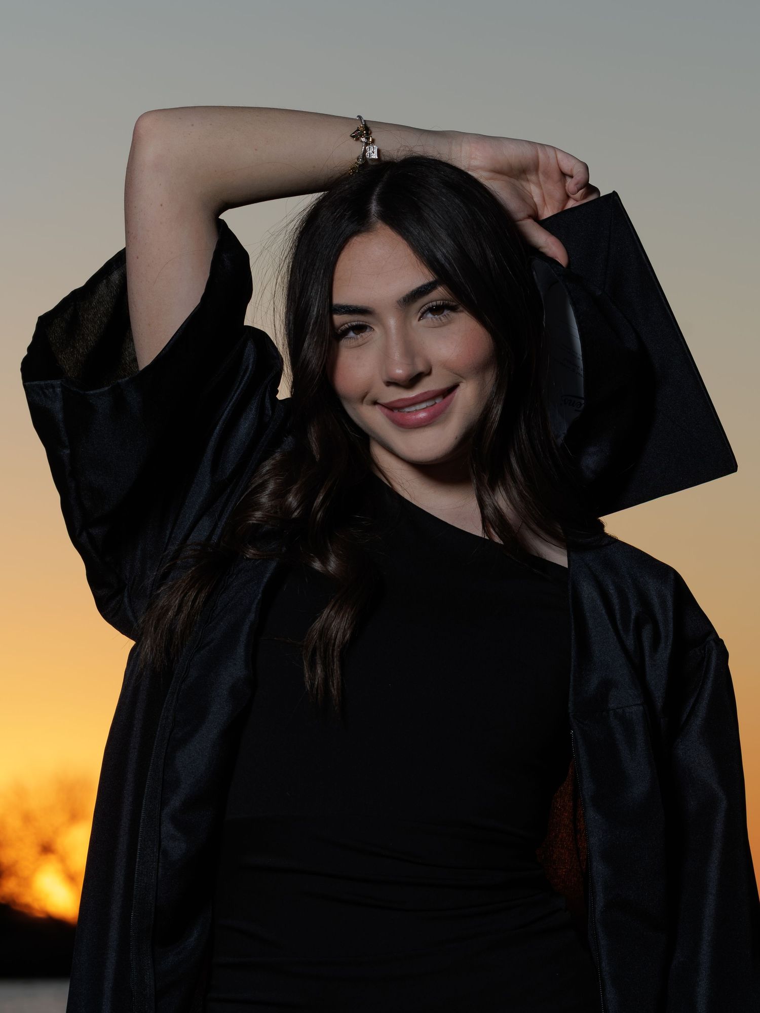 A woman in a black dress poses against a sunset sky in a series of silhouetted photos.