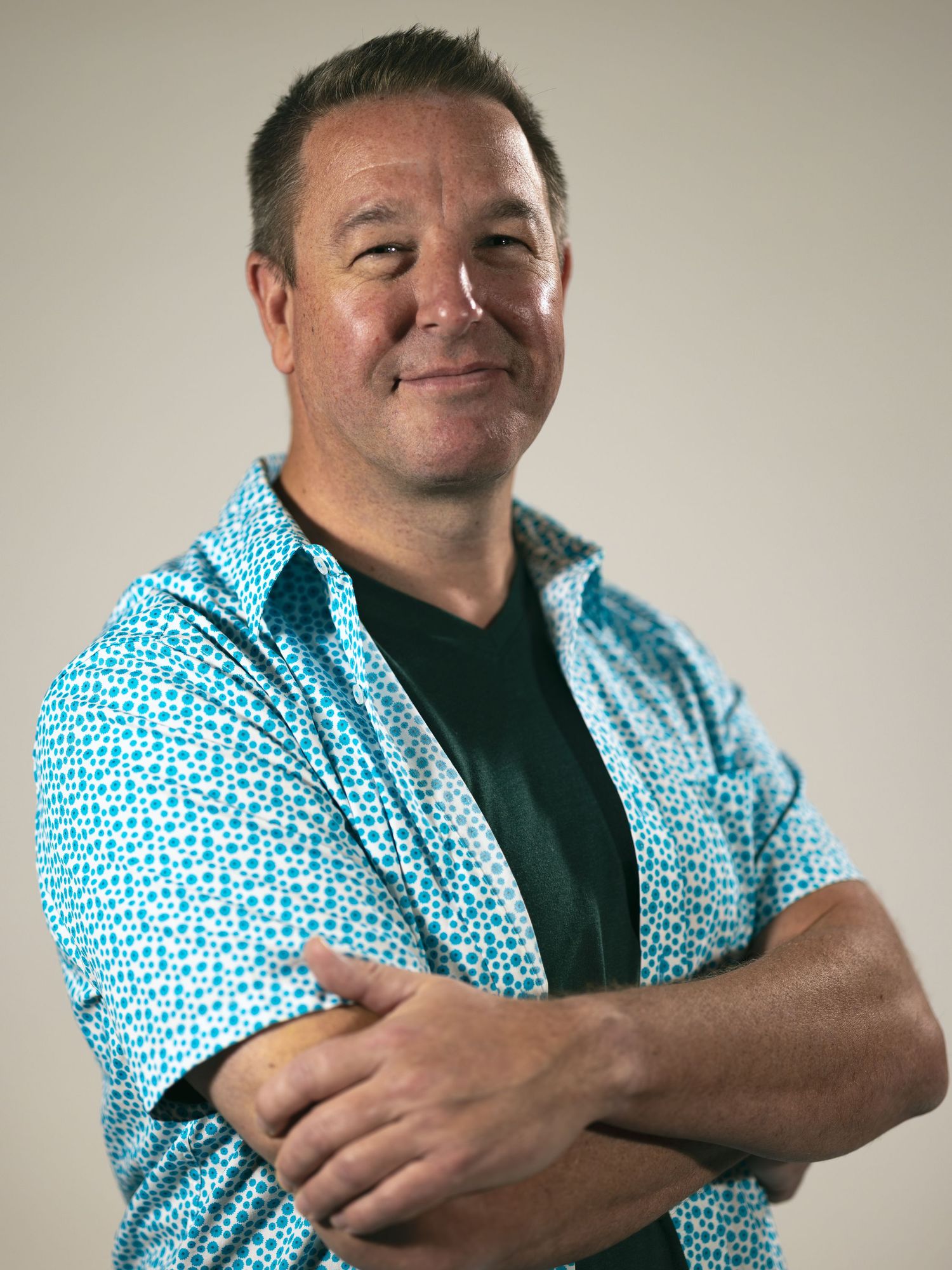 Person in turquoise patterned short-sleeve shirt and black t-shirt shown in multiple poses against neutral background.