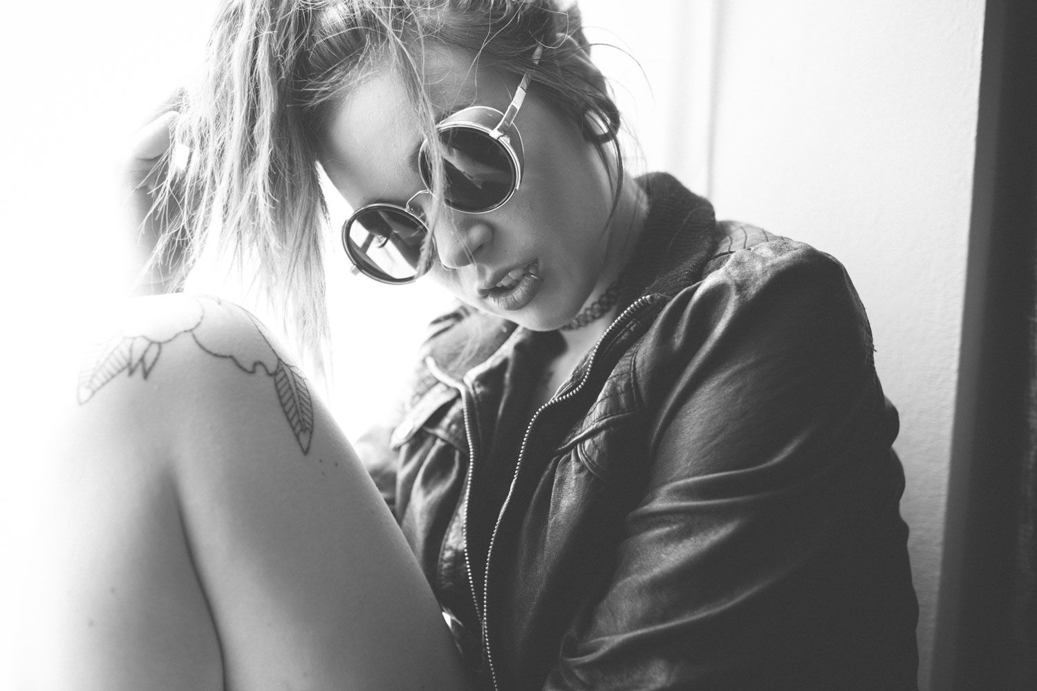 Monochrome close-up of a woman’s face wearing sunglasses, emphasizing timeless and natural beauty and coolness.